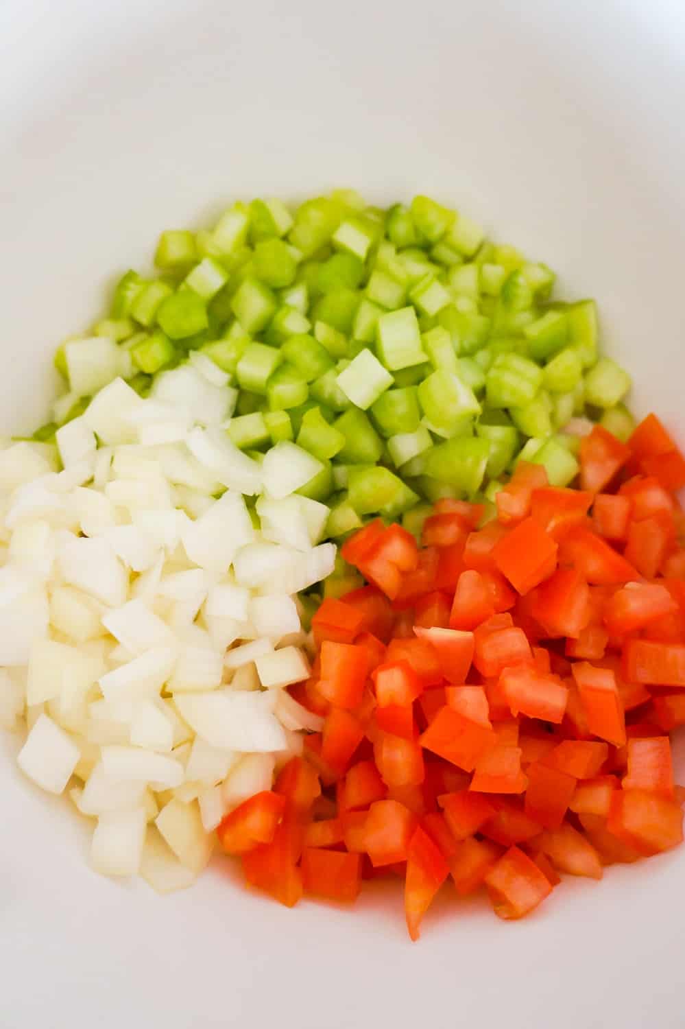 diced celery, diced tomatoes and diced onions in a mixing bowl