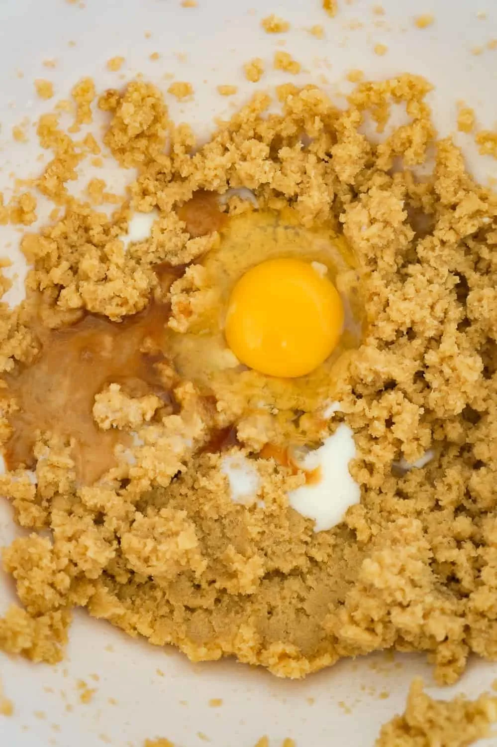 an egg, milk and vanilla extract added to a crisco and brown sugar mixture in a mixing bowl