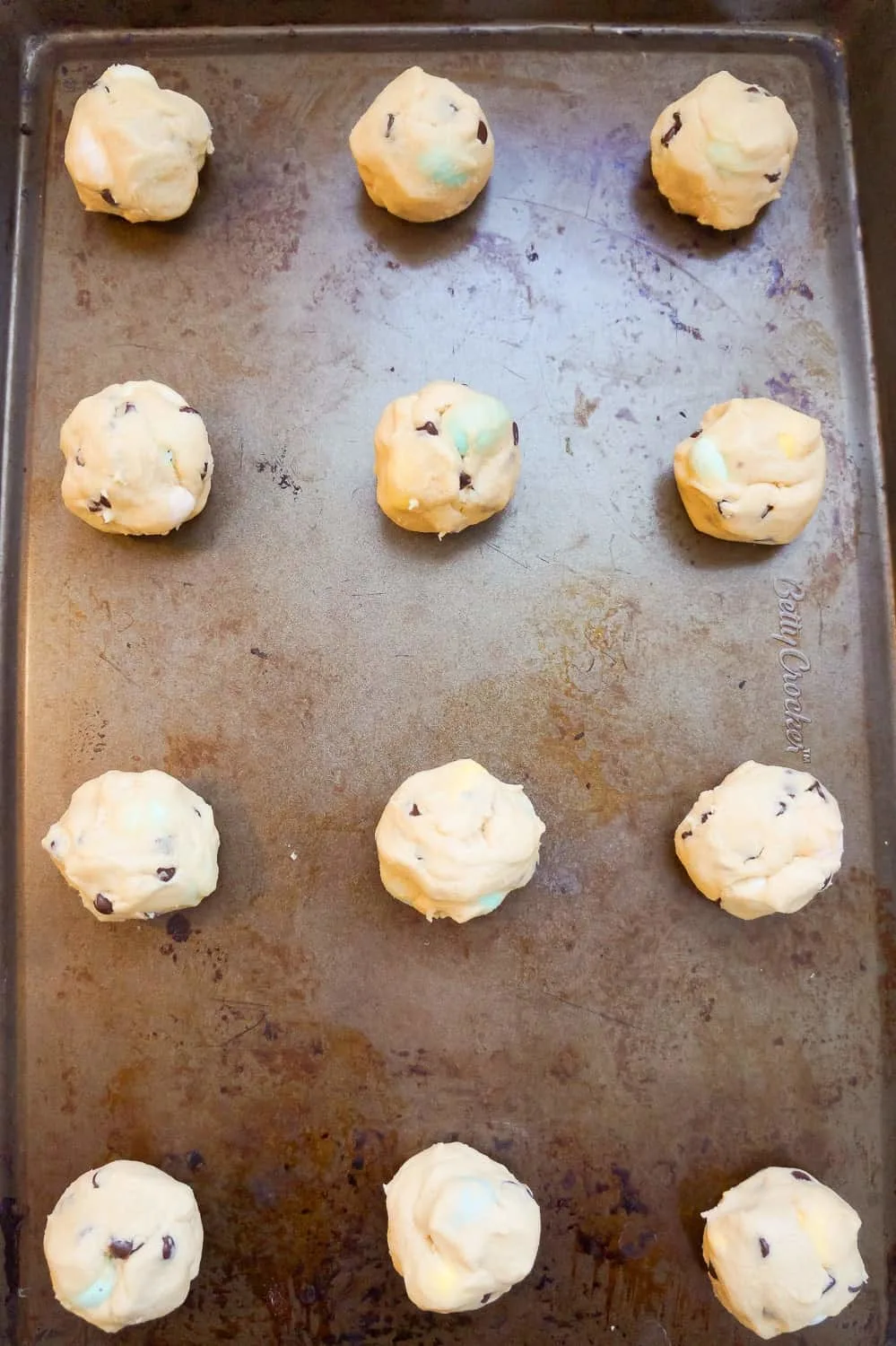 mini egg cookie dough balls on a baking sheet