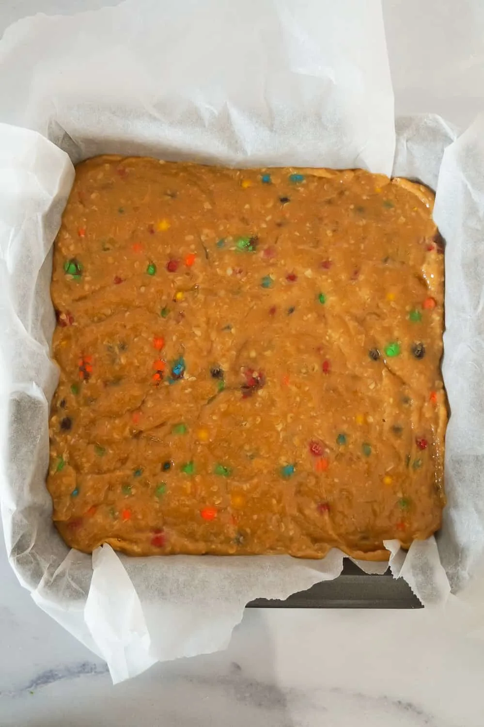 monster cookie dough fudge before chilling in a parchment lined baking pan