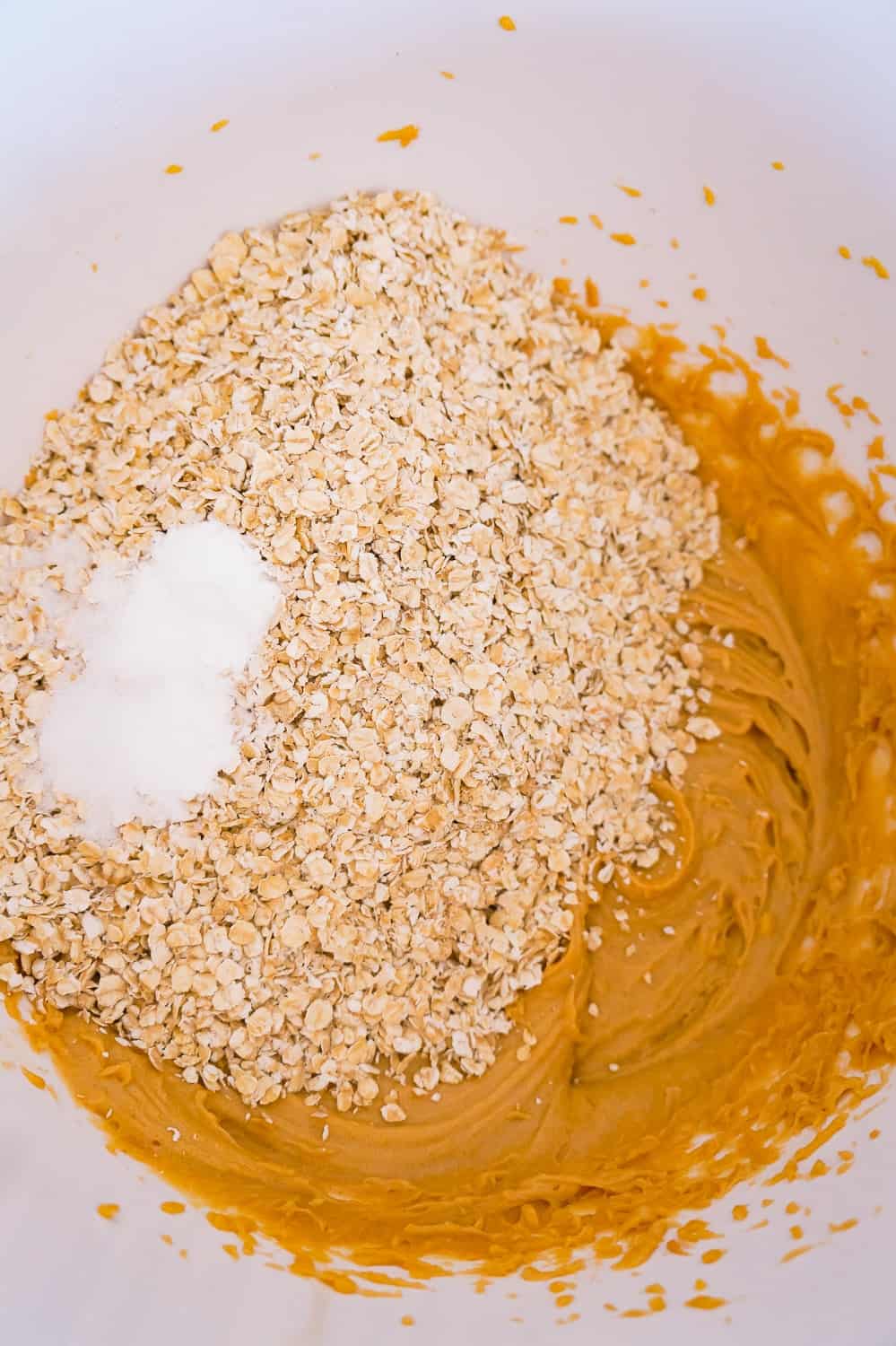 baking powder and quick oats added to peanut butter mixture in a mixing bowl