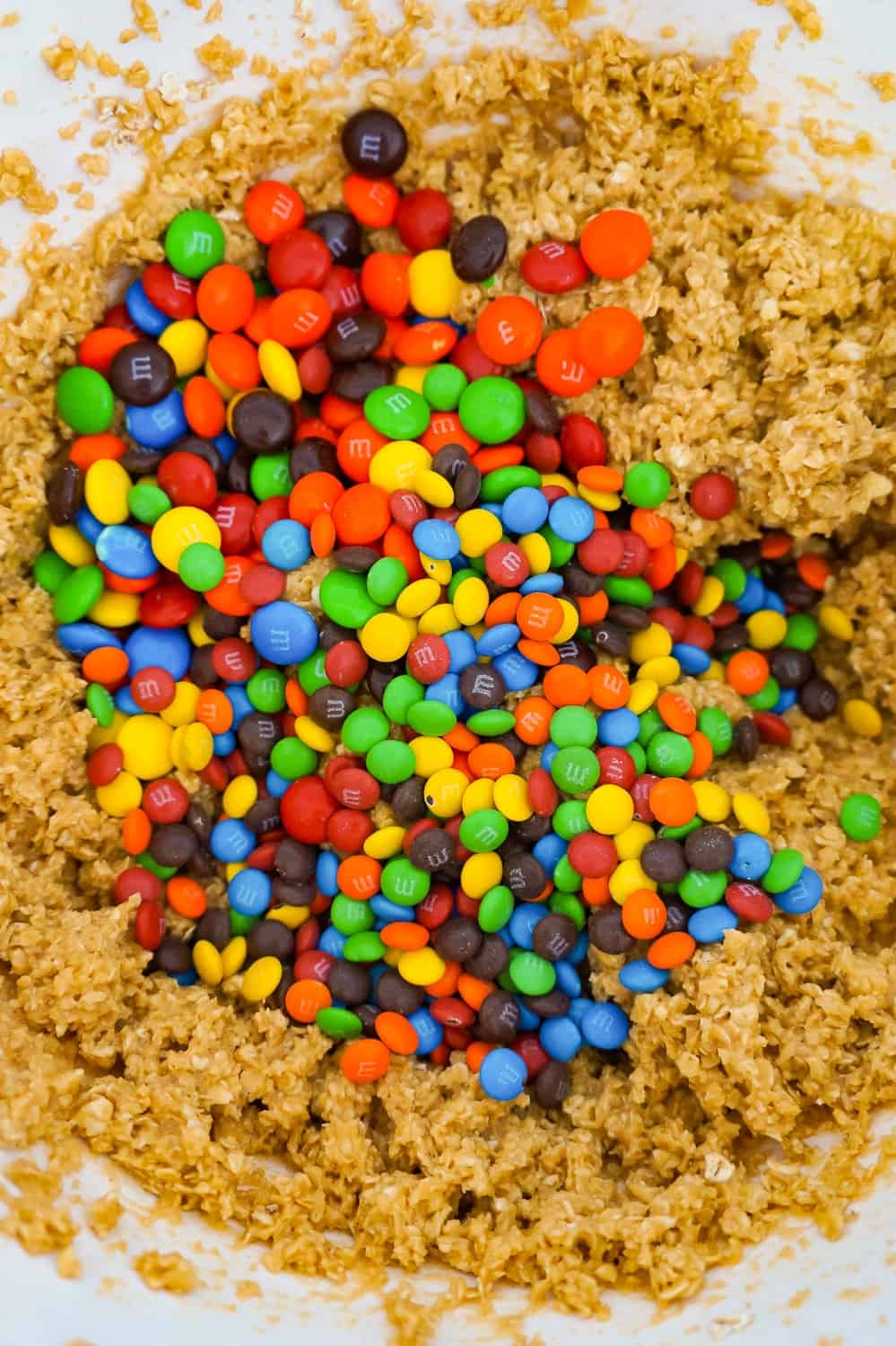 M&M's on top of peanut butter oatmeal cookie dough in a mixing bowl