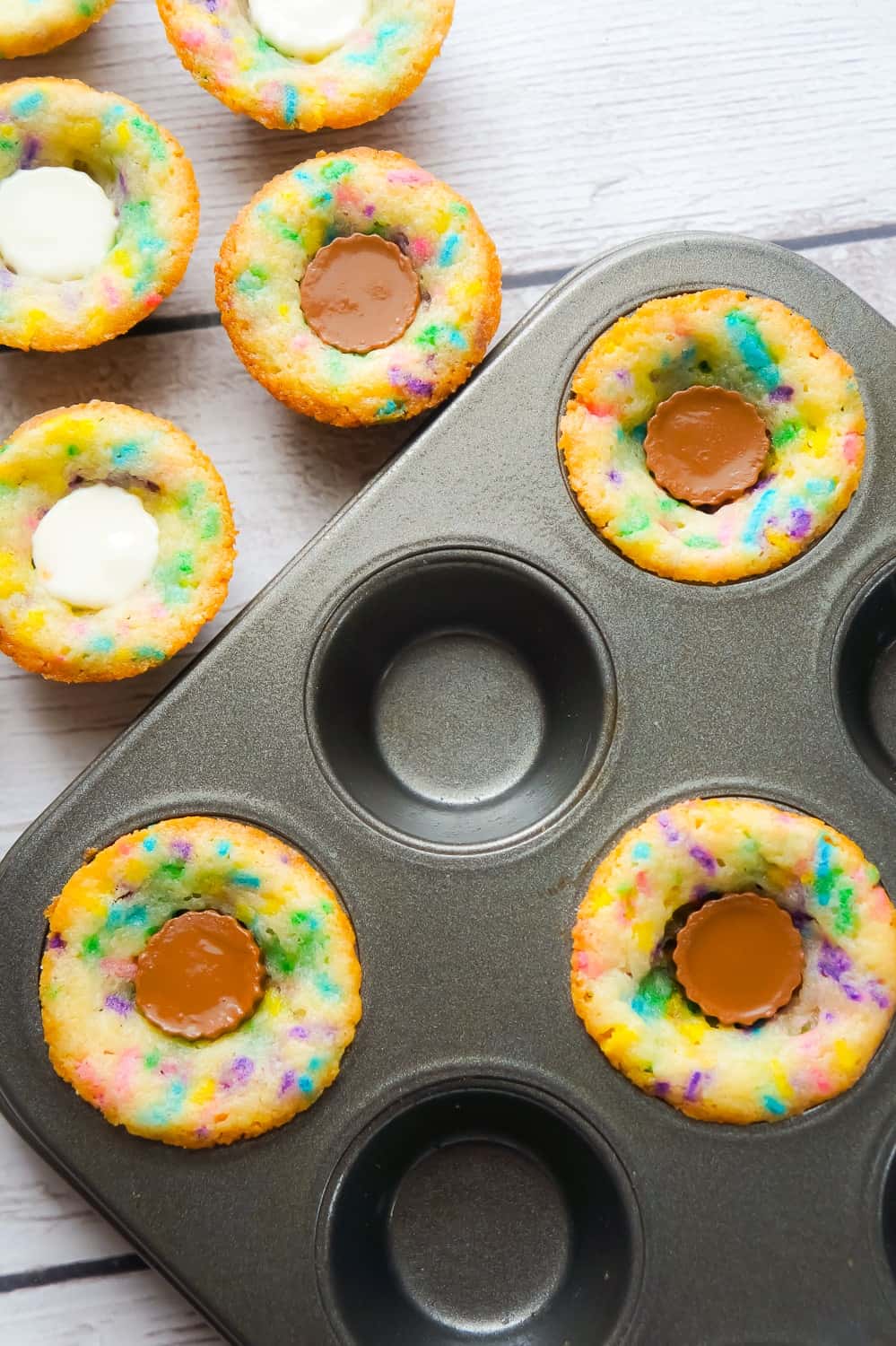 Peanut Butter Cup Sugar Cookies are a cute and colourful dessert perfect for spring. These sugar cookie cups are made in mini muffin tins and contain mini Reese's peanut butter cups and white chocolate peanut butter cups.