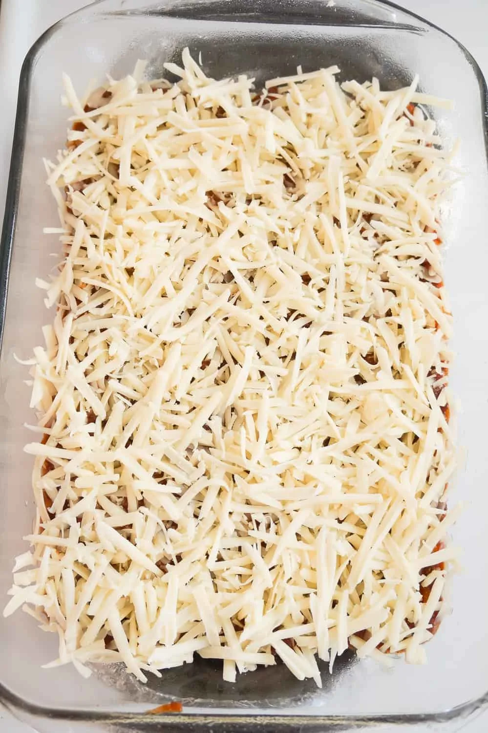 shredded mozzarella cheese on top of sloppy joe mixture in a baking dish