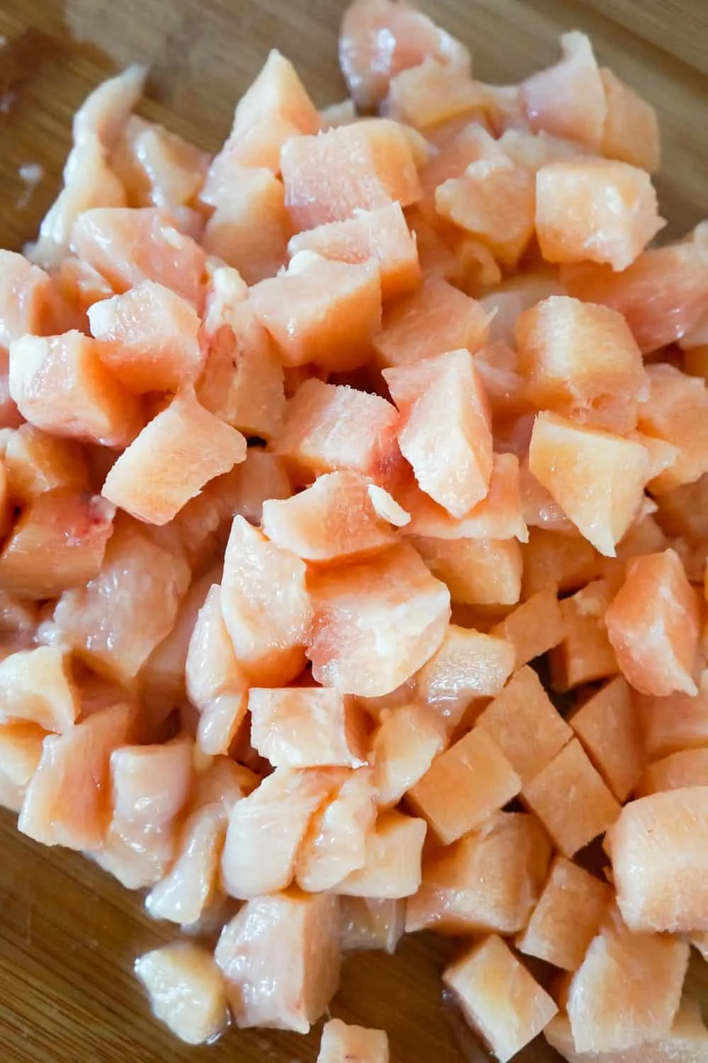 raw chicken breast chunks on a cutting board