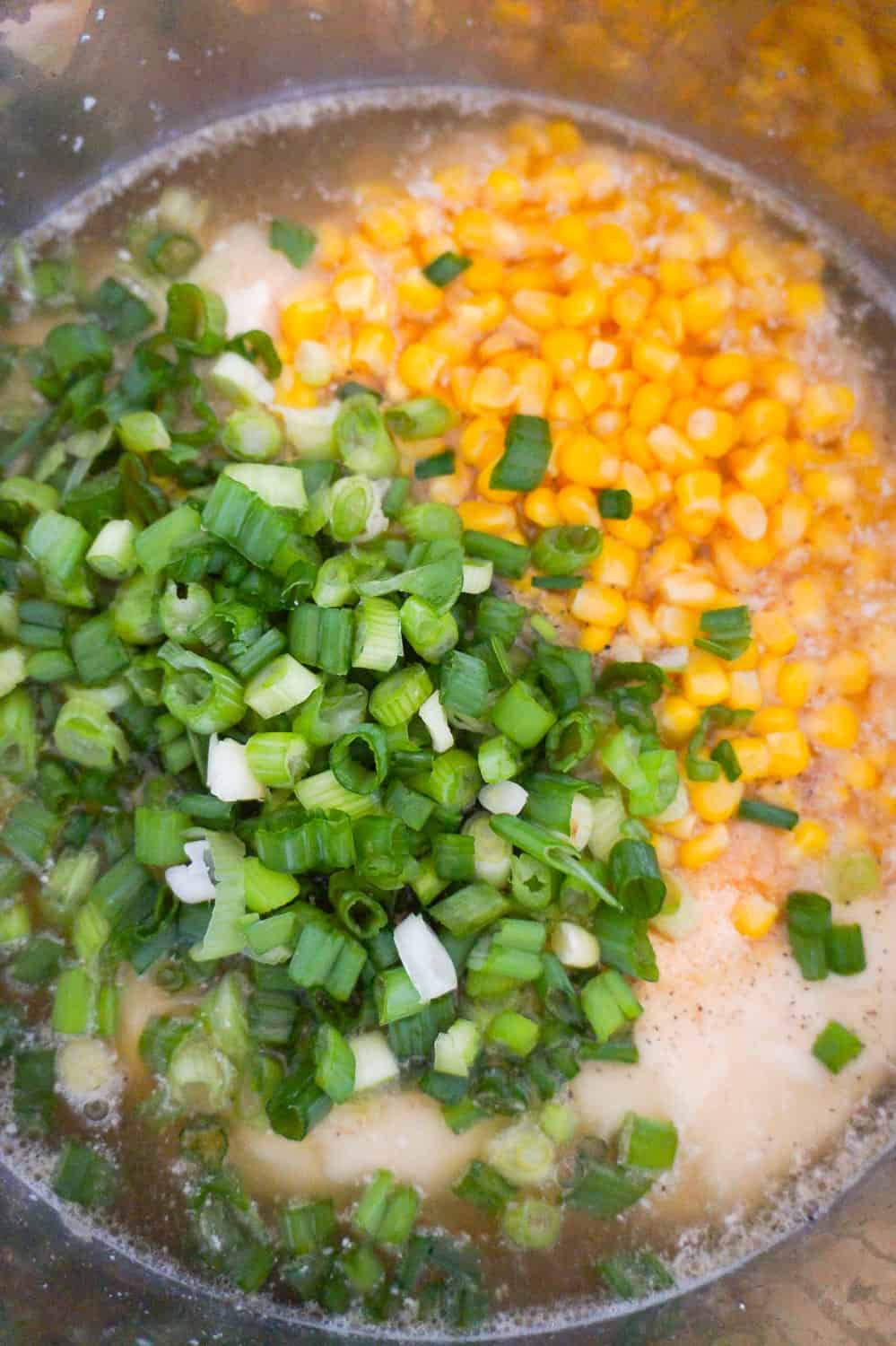 chopped green onions and corn on top of liquid in an Instant Pot