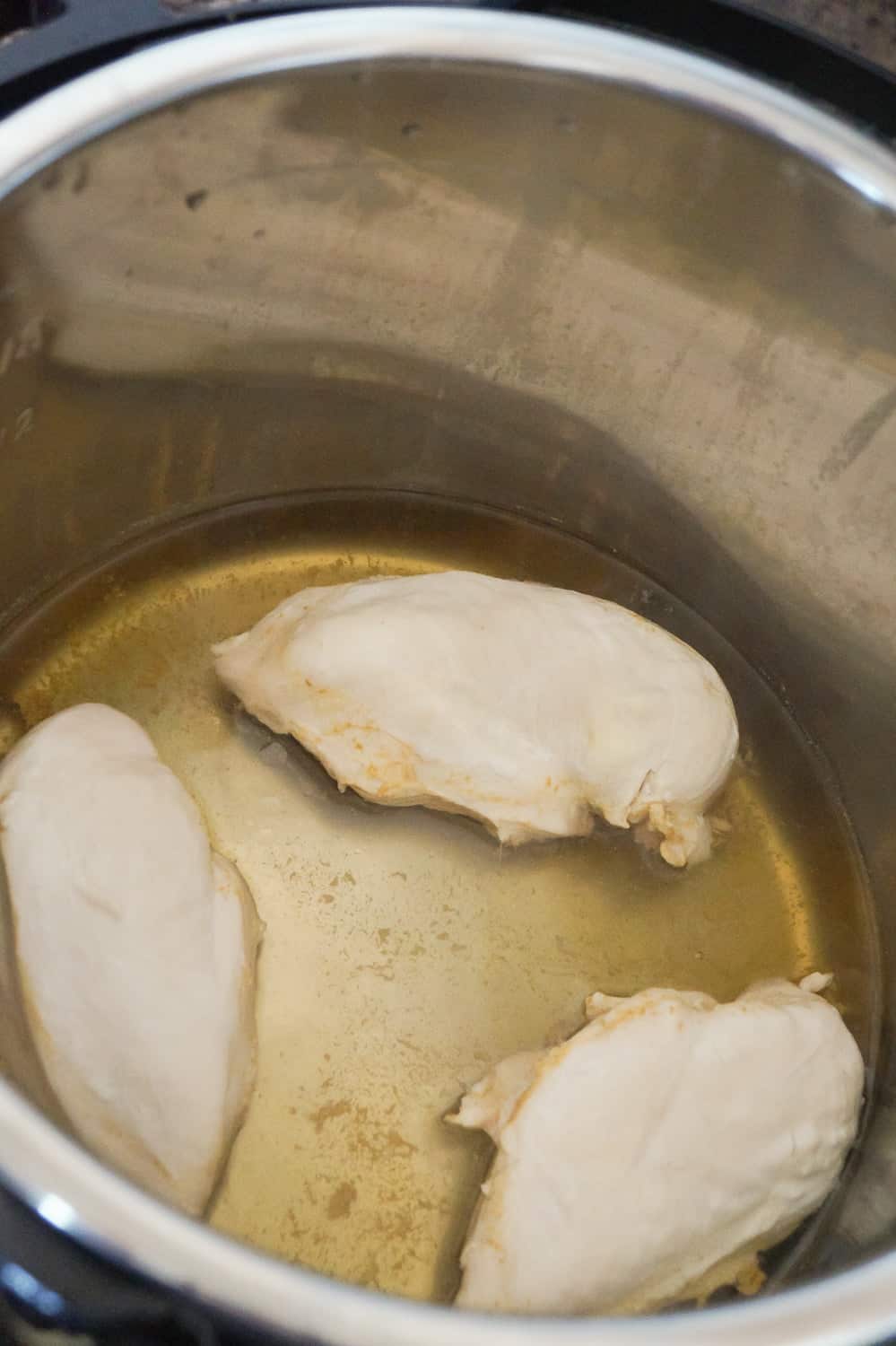 cooked chicken breasts in broth in an Instant Pot