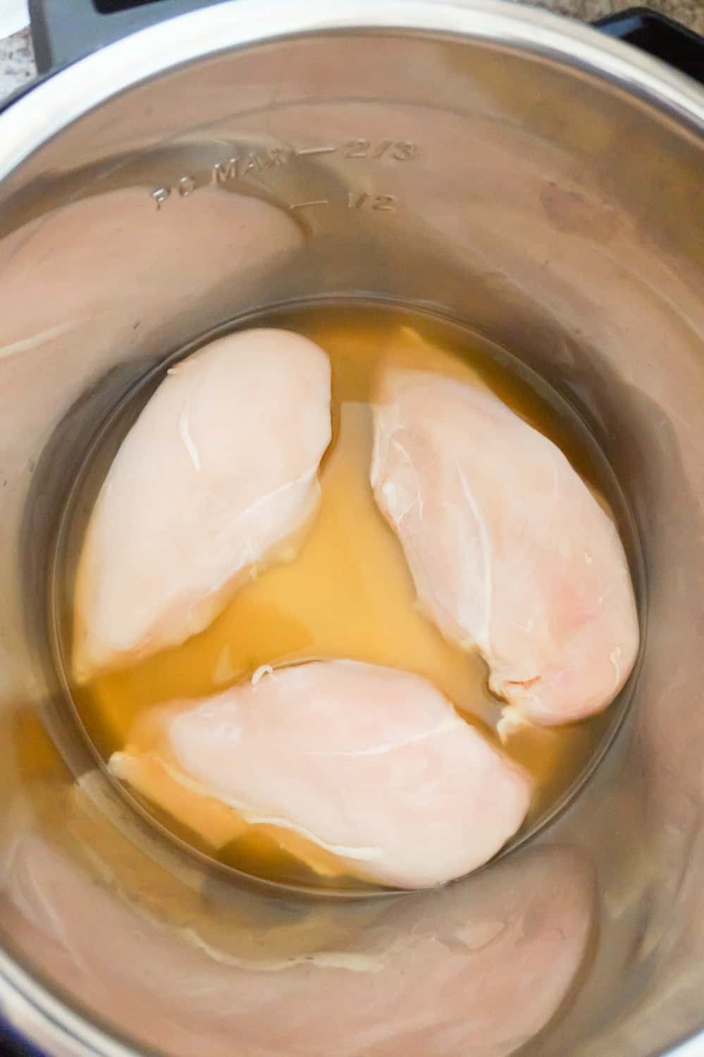 raw chicken breasts in broth in an Instant Pot