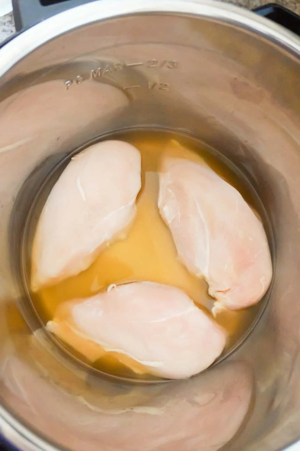 raw chicken breasts in broth in an Instant Pot