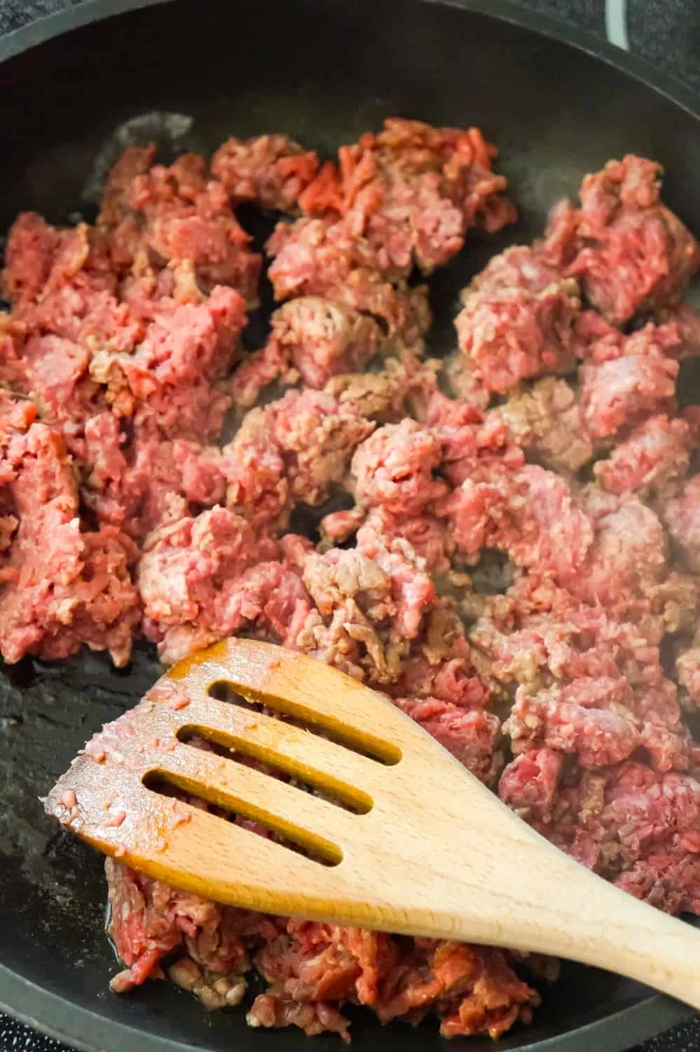 raw ground beef cooking in a frying pan