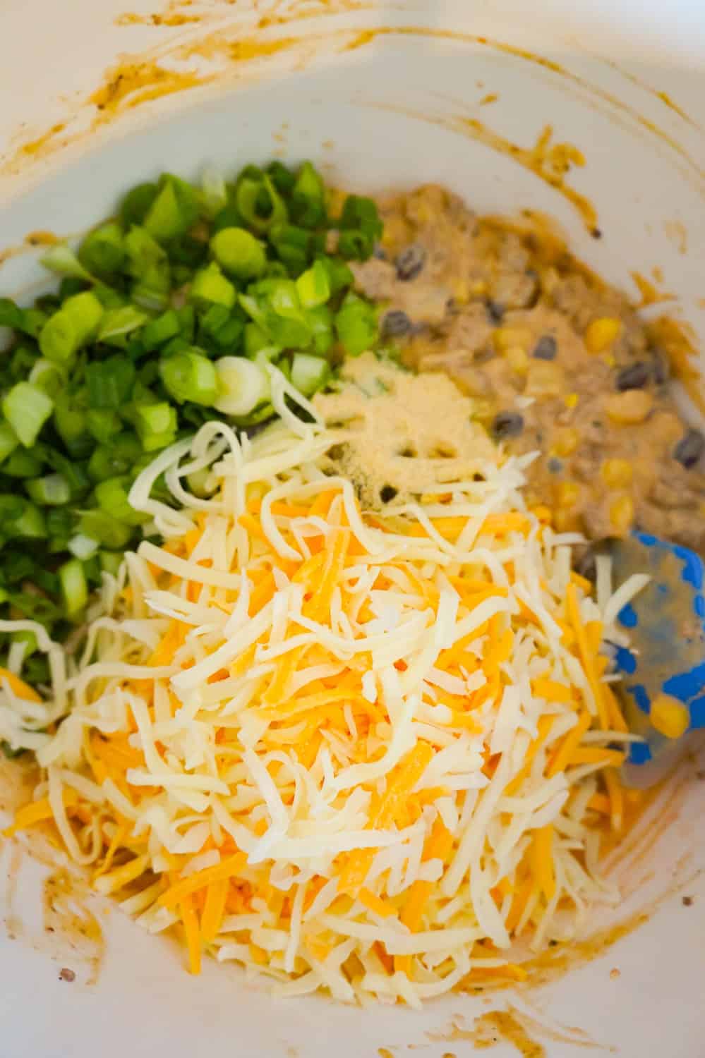 shredded cheese, chopped green onions and ground beef mixture in a mixing bowl