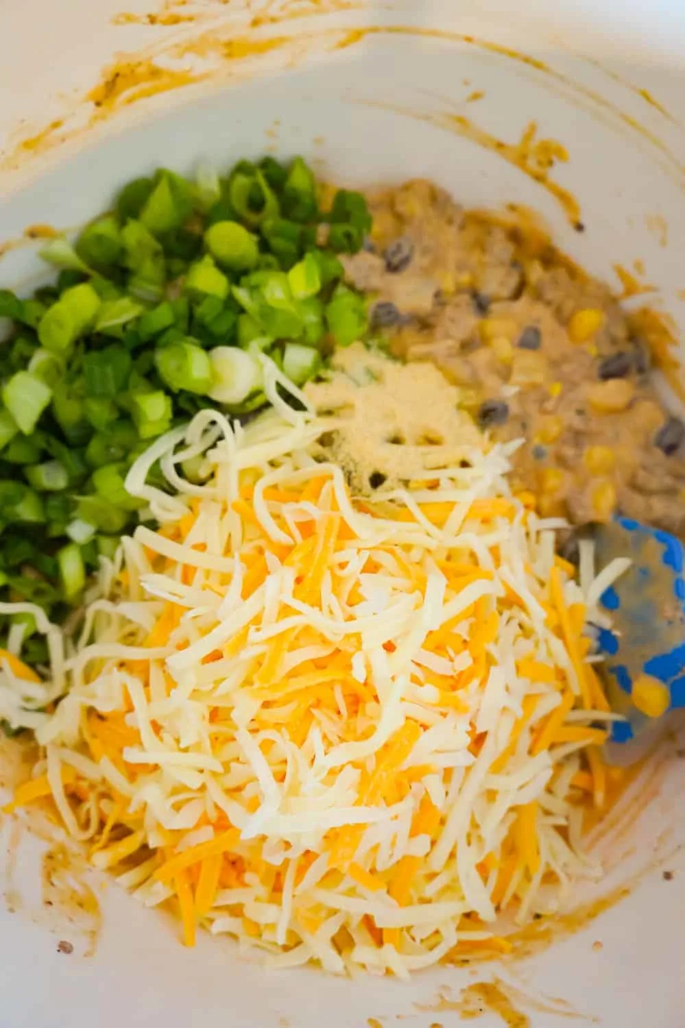 shredded cheese, chopped green onions and ground beef mixture in a mixing bowl