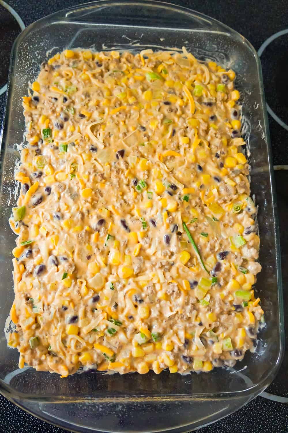 ground beef mixture with corn and black beans pressed into a 9 x 13 inch baking dish