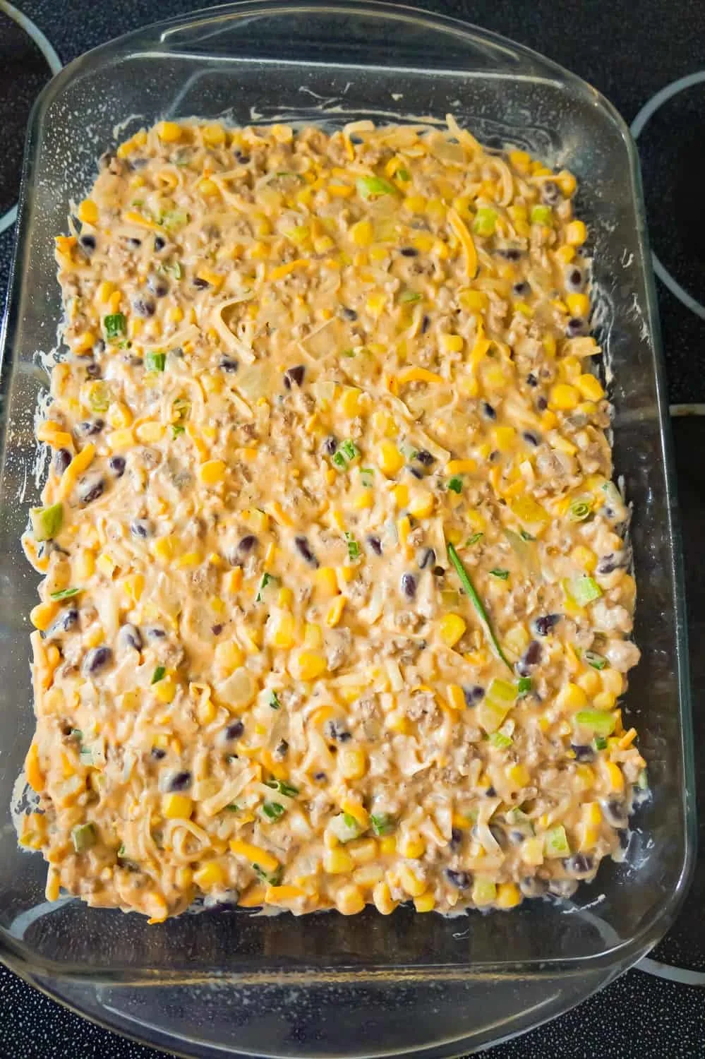 ground beef mixture with corn and black beans pressed into a 9 x 13 inch baking dish