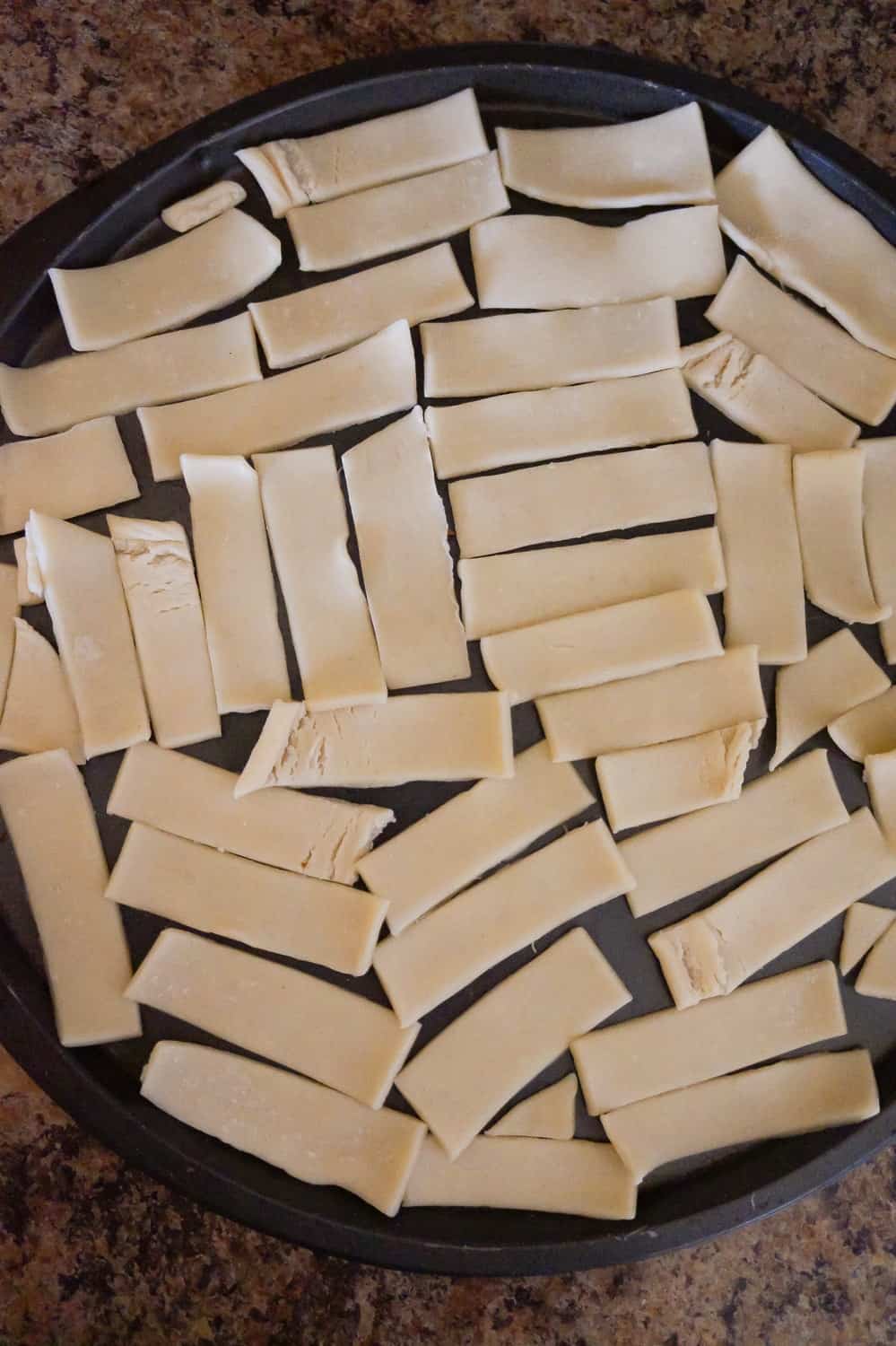 strips of pie crust dough spread out on baking sheet