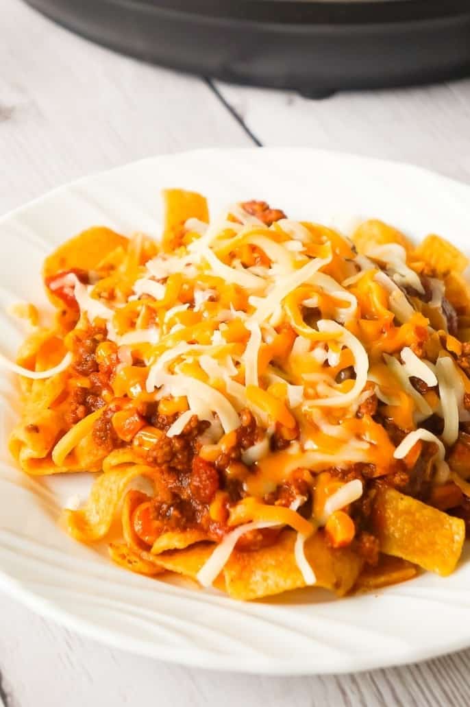 Instant Pot Frito Pie is an easy ground beef dinner recipe the whole family will love. A delicious ground beef and corn chili mixture is cooked in the Instant Pot and then poured over Frito's corn chips and topped with shredded cheese.