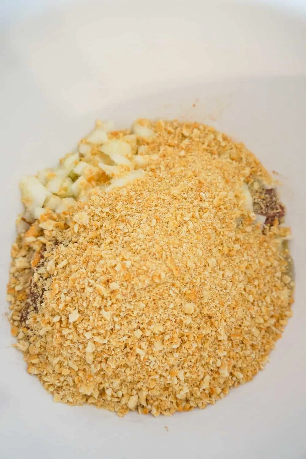 crushed ritz crackers on top of other meatloaf ingredients in a mixing bowl