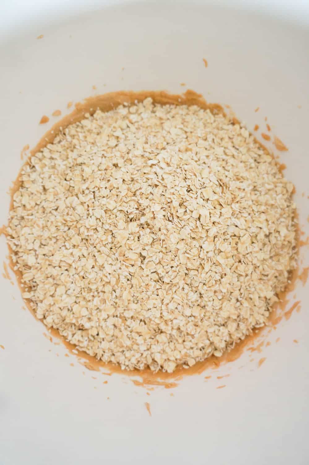 quick oats on top of peanut butter mixture in a mixing bowl