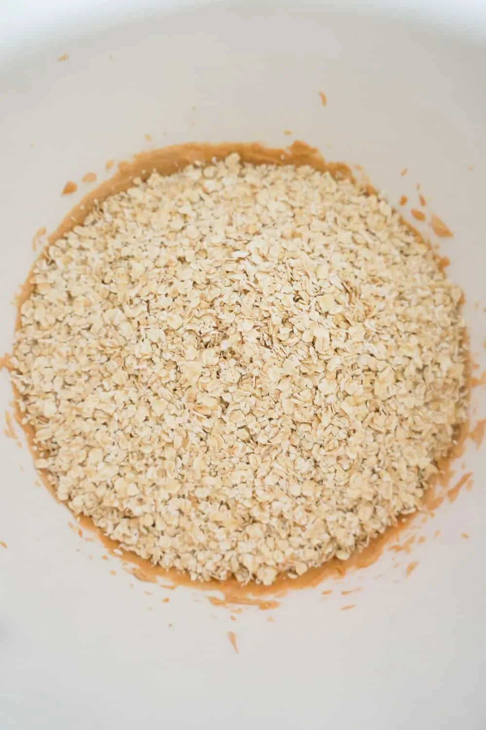 quick oats on top of peanut butter mixture in a mixing bowl
