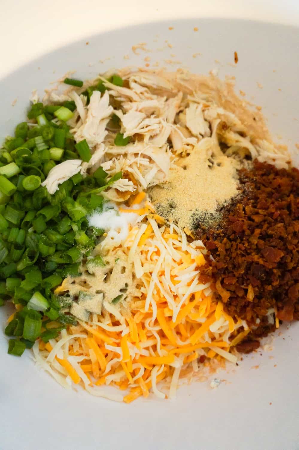 chopped green onions, crumbled bacon, shredded chicken and seasonings in a mixing bowl