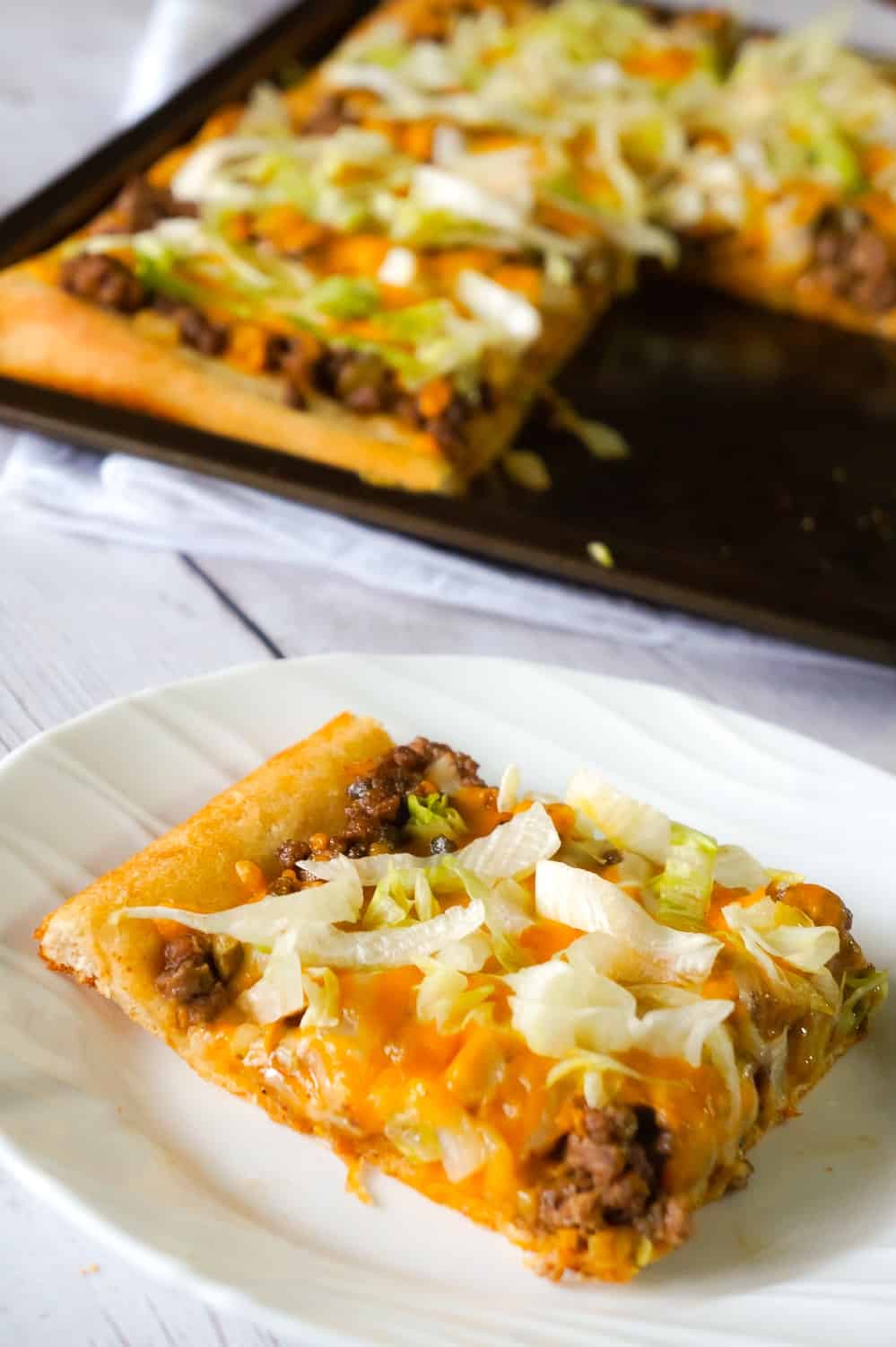 Big Mac Pizza is an easy ground beef dinner recipe that will please both kids and adults. This simple pizza is made with Pillsbury crust and loaded with ground beef, onions, dill pickles, cheddar cheese, homemade Big Mac sauce and shredded lettuce.