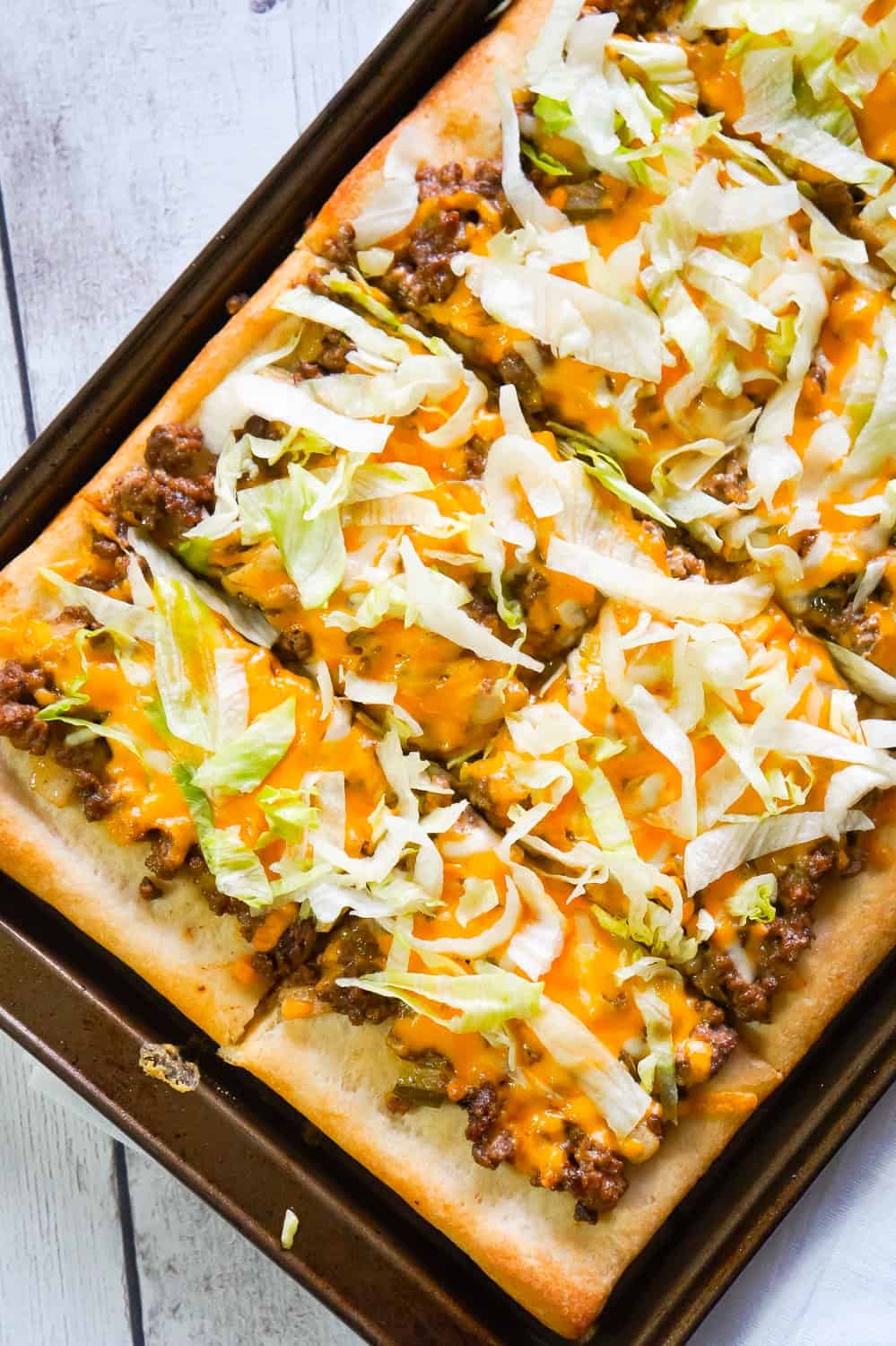 Big Mac Pizza is an easy ground beef dinner recipe that will please both kids and adults. This simple pizza is made with Pillsbury crust and loaded with ground beef, onions, dill pickles, cheddar cheese, homemade Big Mac sauce and shredded lettuce.