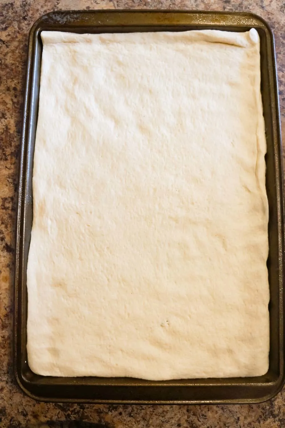 Pillsbury pizza crust pressed out on a baking sheet