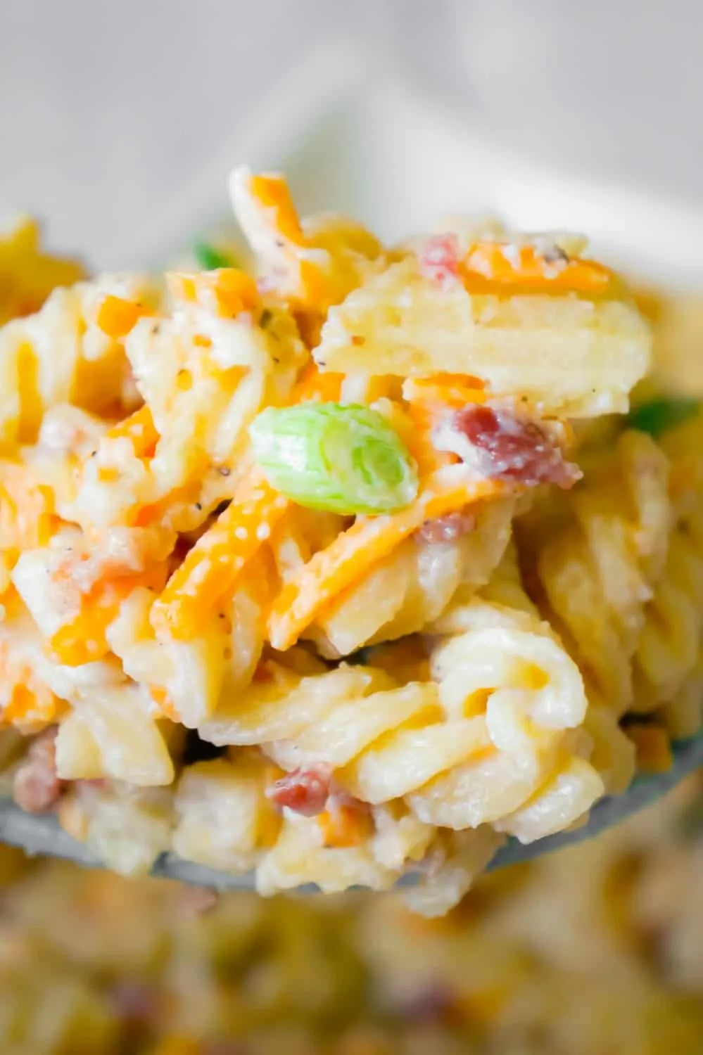 Cheddar Bacon Ranch Pasta Salad is a quick and easy cold side dish recipe perfect for summer. This creamy pasta salad is loaded with shredded cheddar cheese, bacon, green onions and crumbled potato chips.