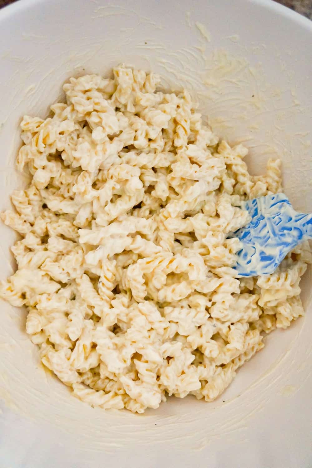 cooked fusilli coated in mayo and ranch dressing in a mixing bowl