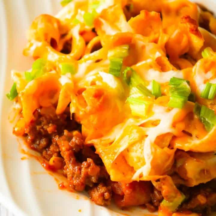 Frito Pie is an easy ground beef dinner recipe the whole family will love. This ground beef casserole starts with a chili base and is topped with Frito's corn chips, shredded cheese and green onions.