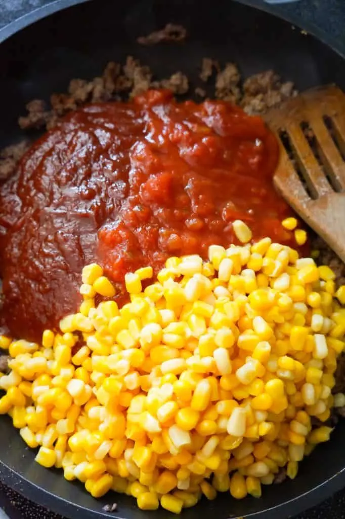 chili sauce, salsa and corn on top of ground beef in a frying pan
