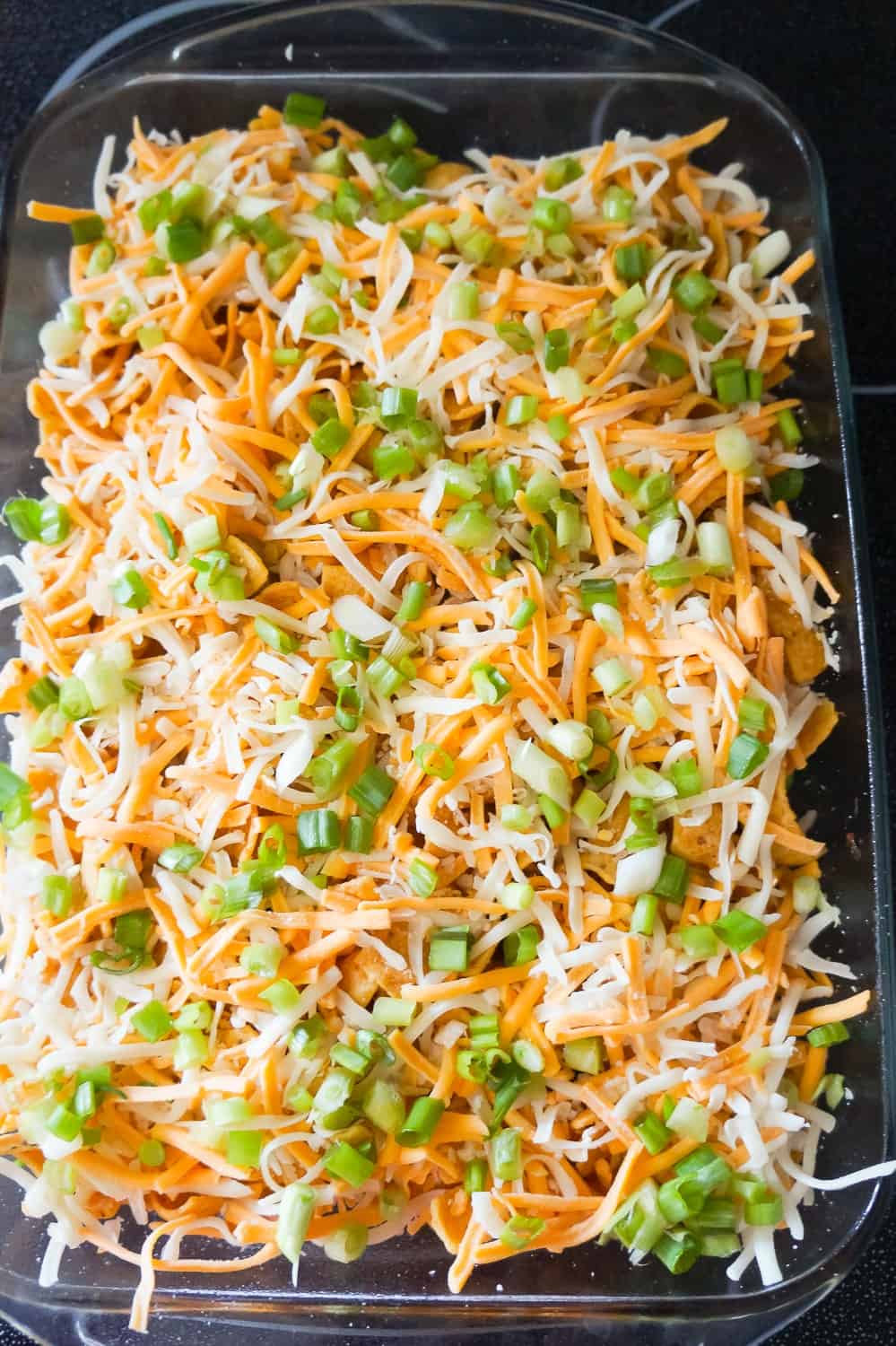 shredded cheese and green onions on top of Frito pie before baking