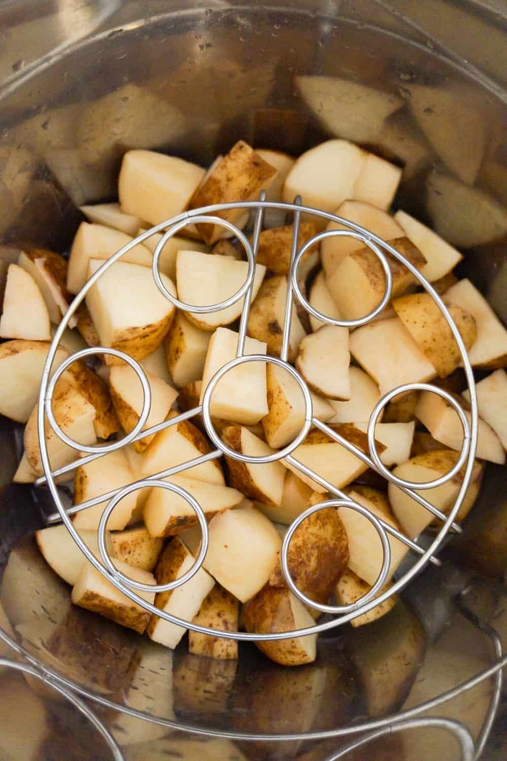 trivet on top of raw potato chunks in an Instant Pot