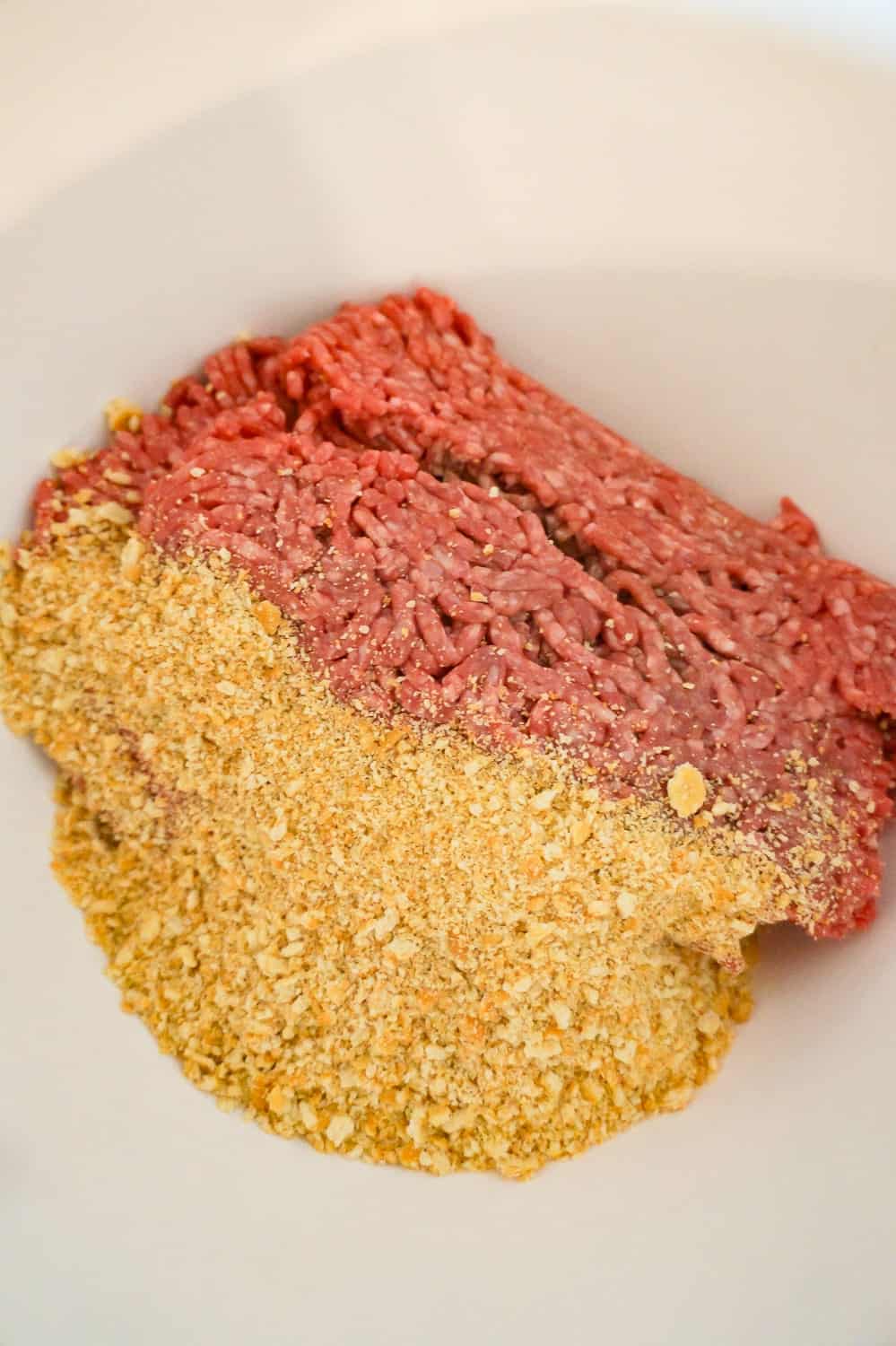 raw ground beef and Ritz cracker crumbs in a mixing bowl