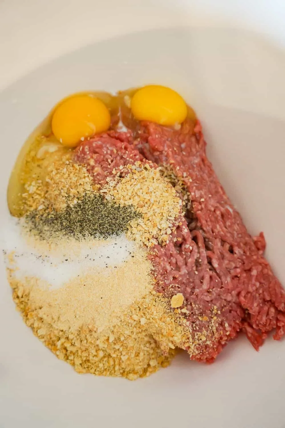 raw ground beef, eggs, Ritz cracker crumbs and spices in a mixing bowl