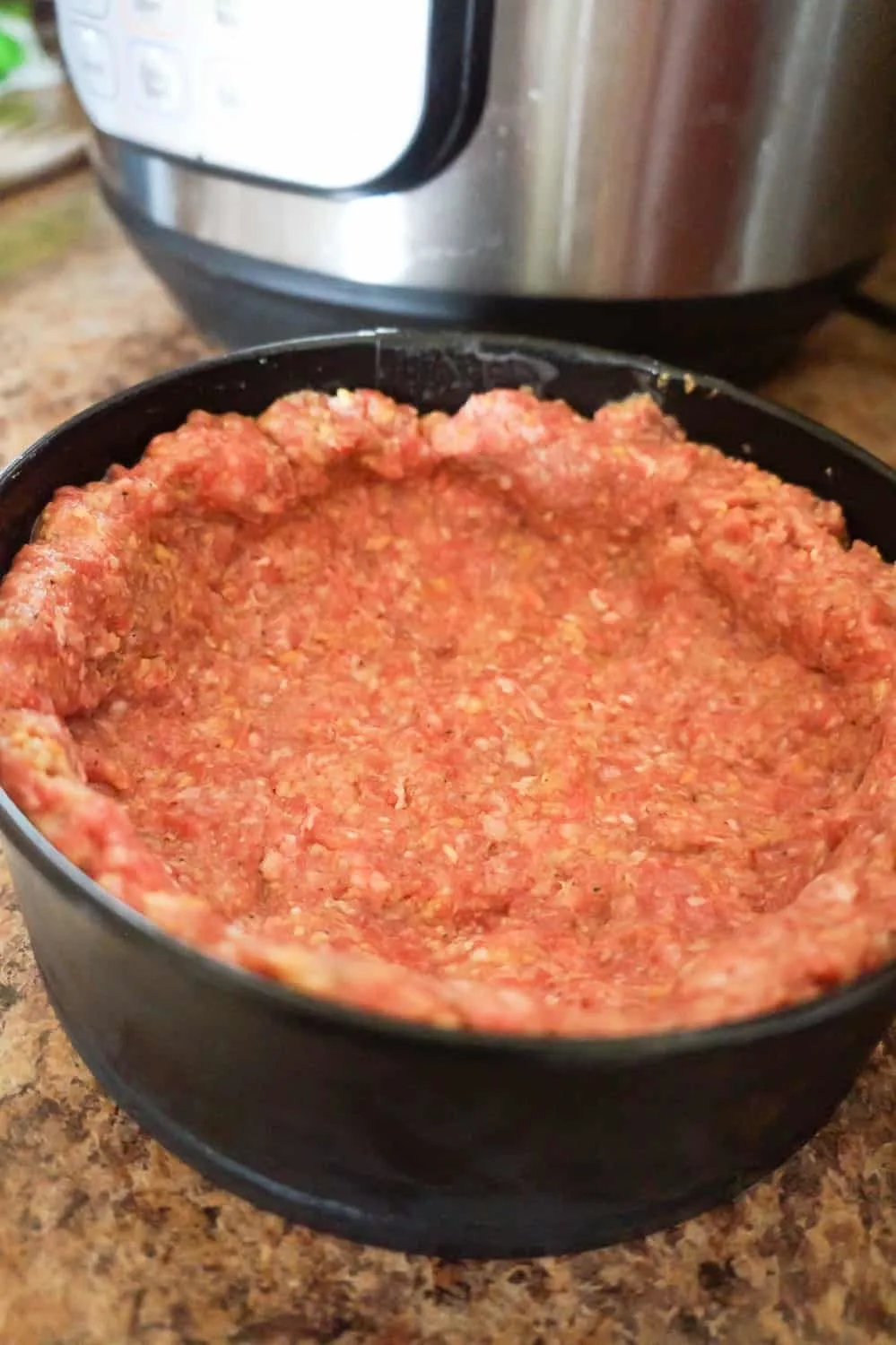 raw ground beef in a spring form pan
