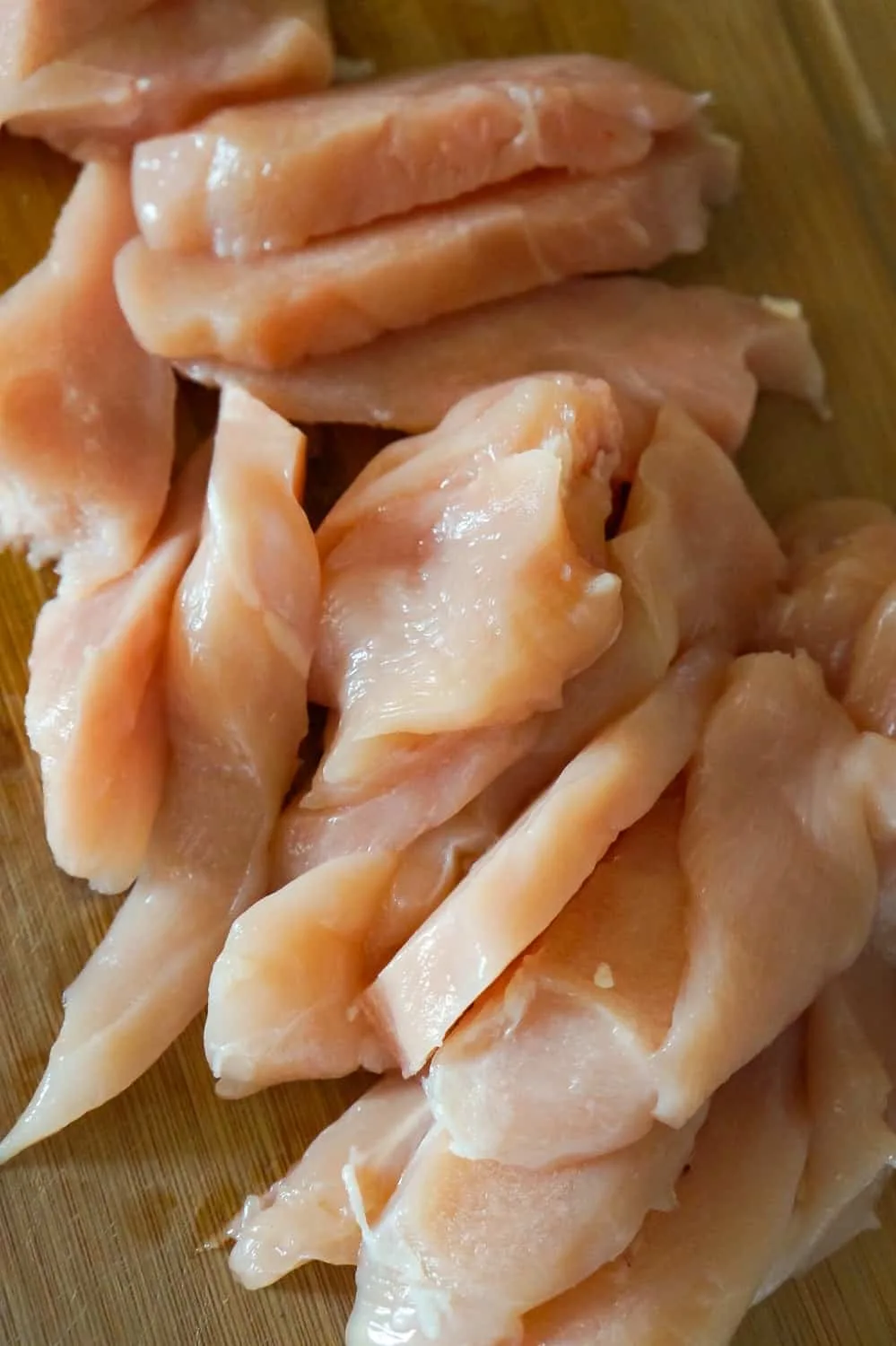 raw chicken breast strips on a cutting board