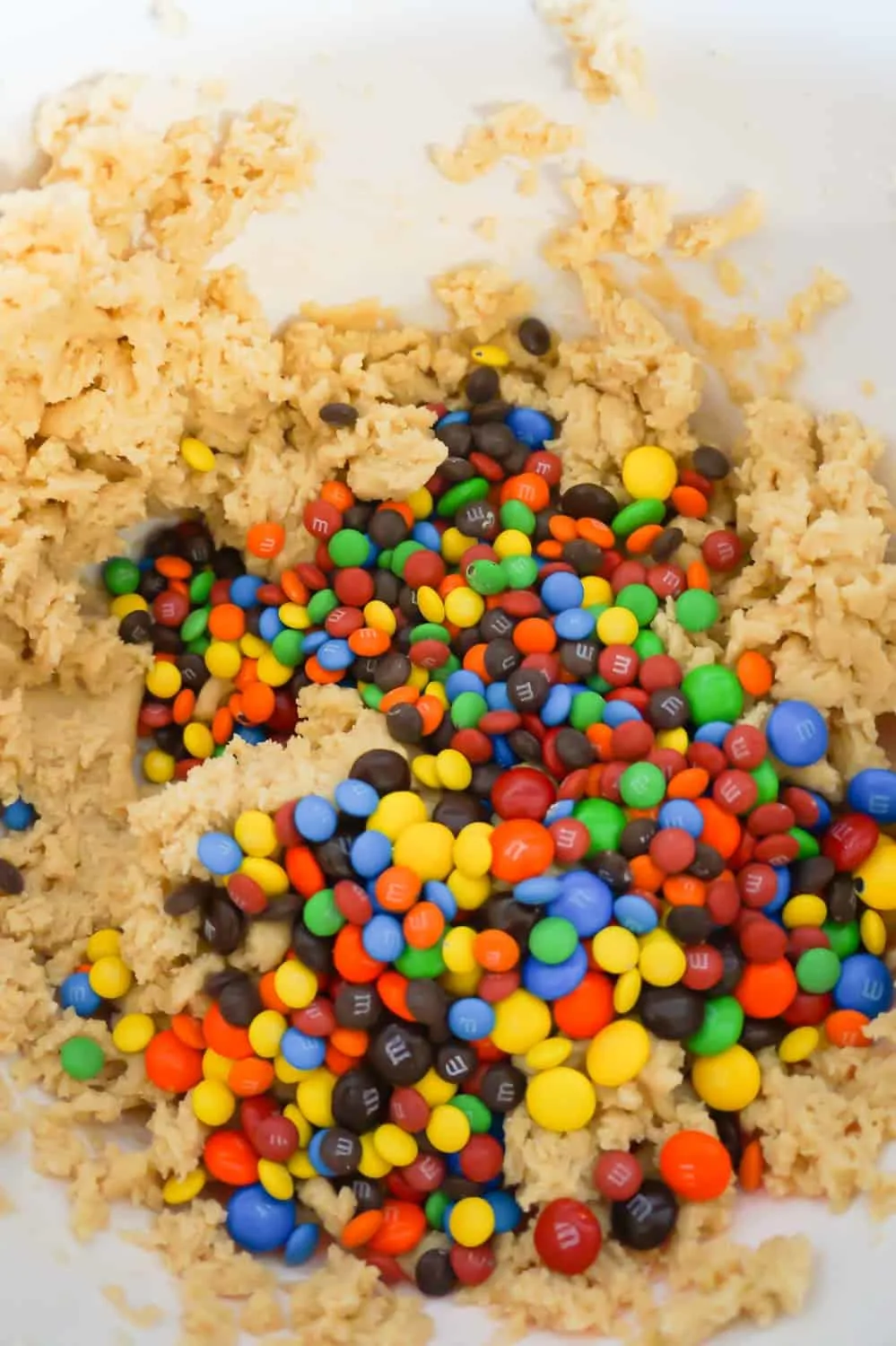 M&Ms and mini M&Ms on top of cookie dough in a mixing bowl