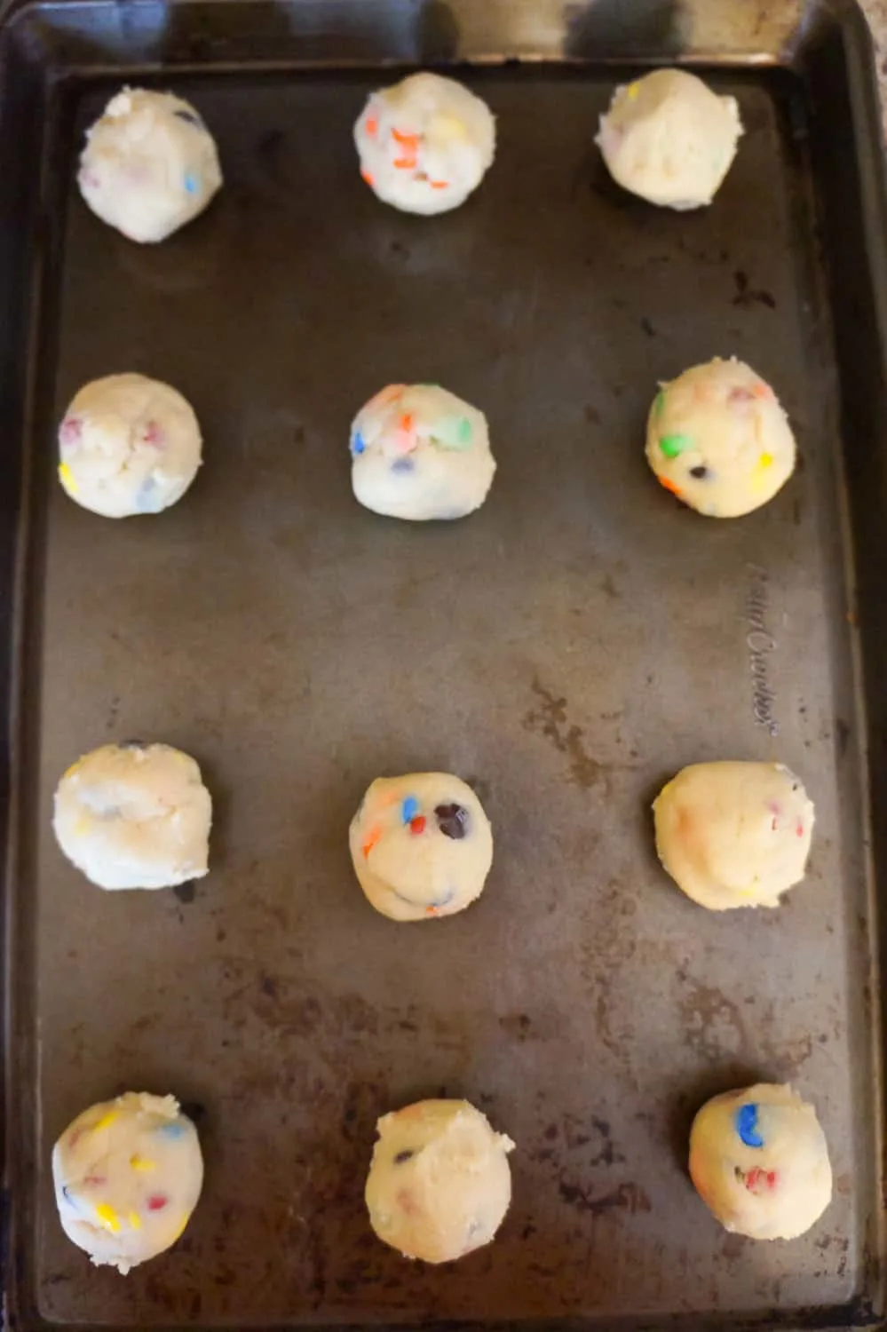 M&M cookie dough balls on a baking sheet