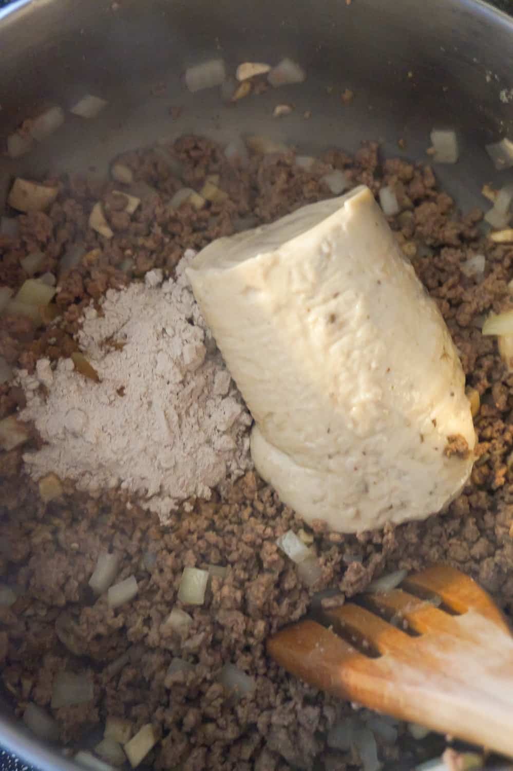 gravy mix and cream of mushroom soup on top of cooked ground beef in a pot