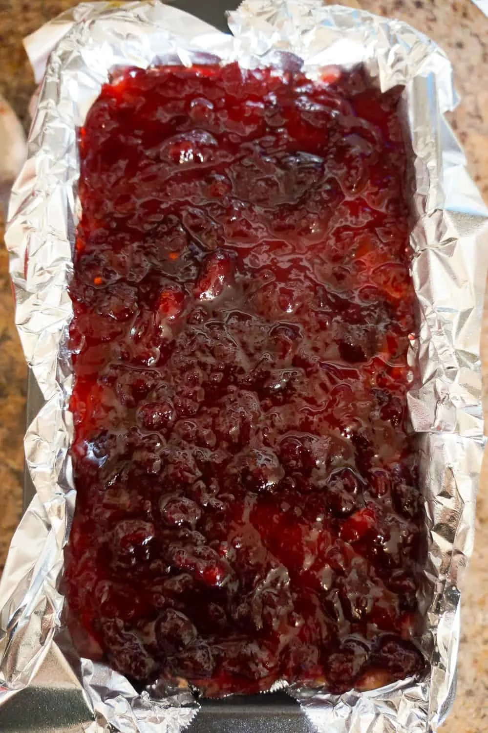 cranberry sauce on top of turkey meatloaf in a loaf pan