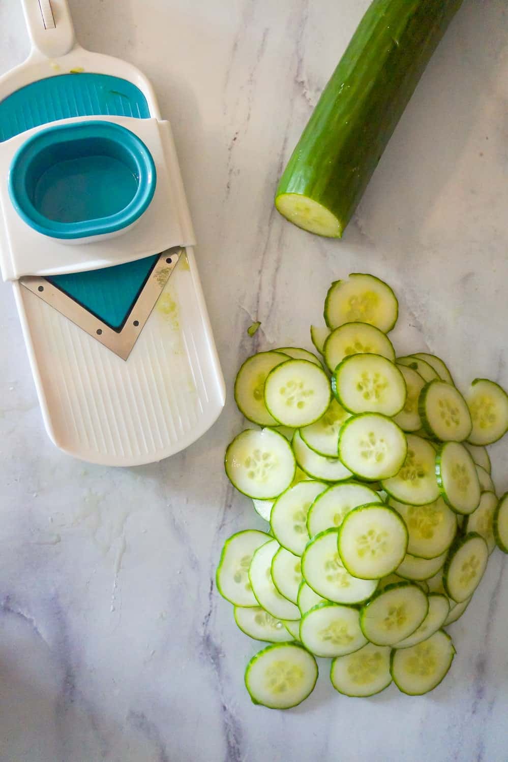 thinly sliced cucumbers next to a mandoline slicer