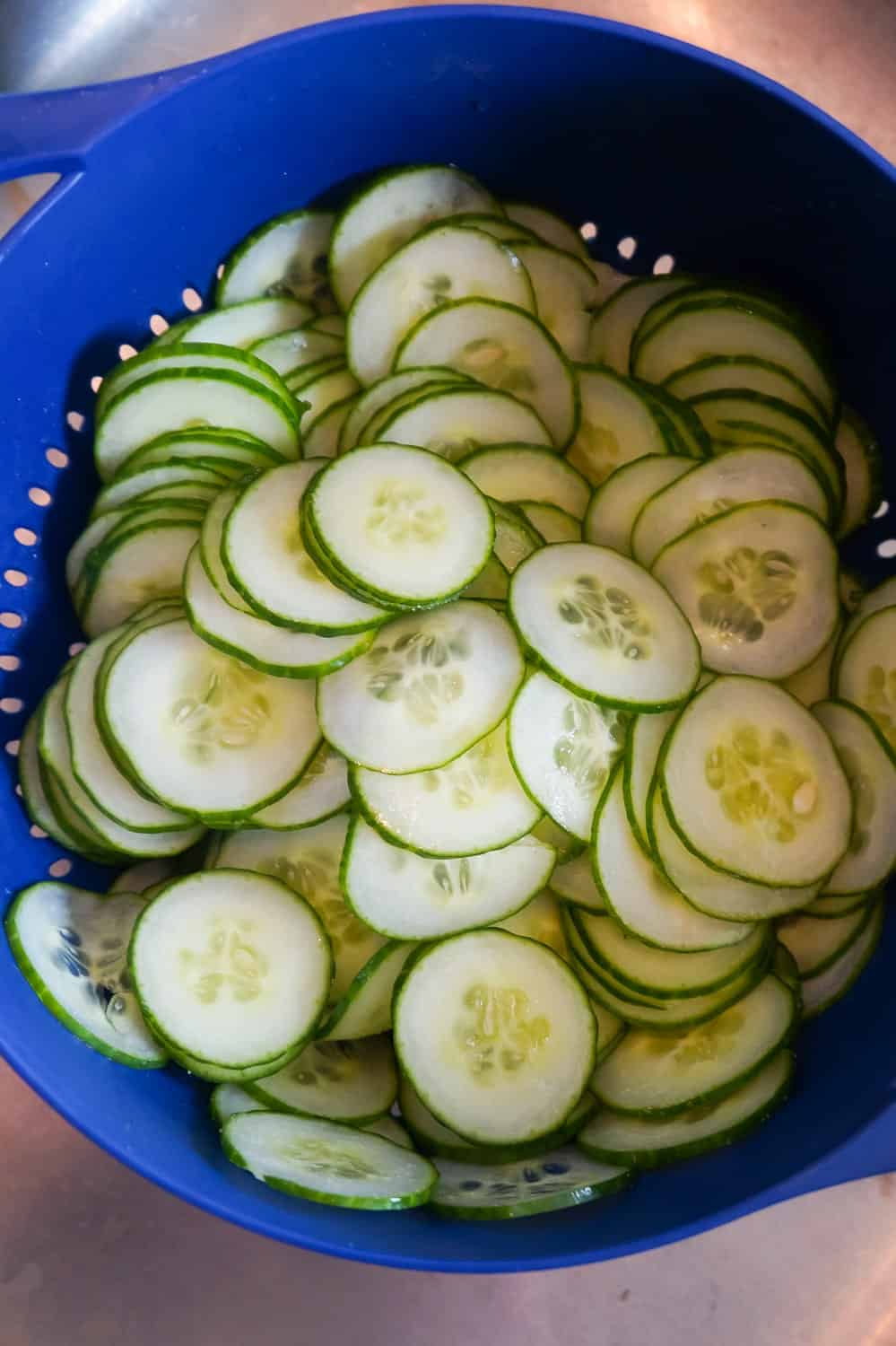 thinly sliced cucumbers tossed with salt in a colander