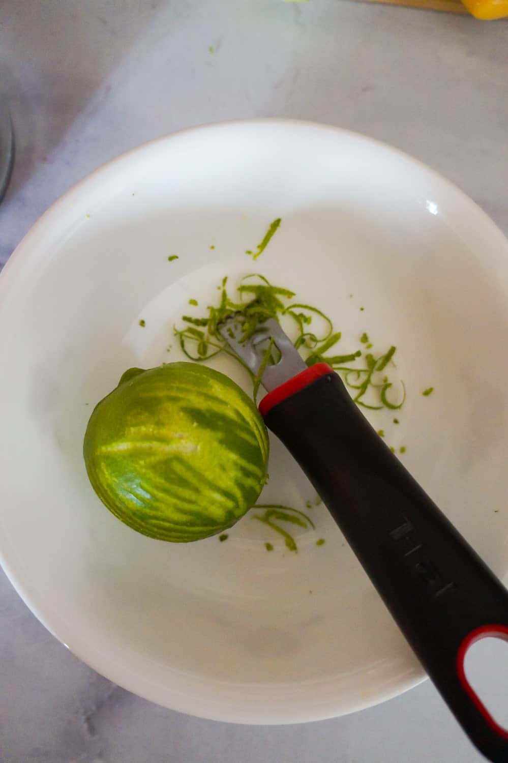 a lime in a bowl with a zester