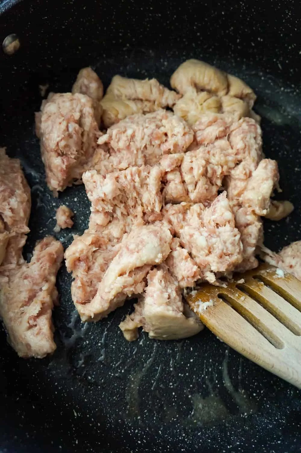 raw pork sausage meat in a frying pan