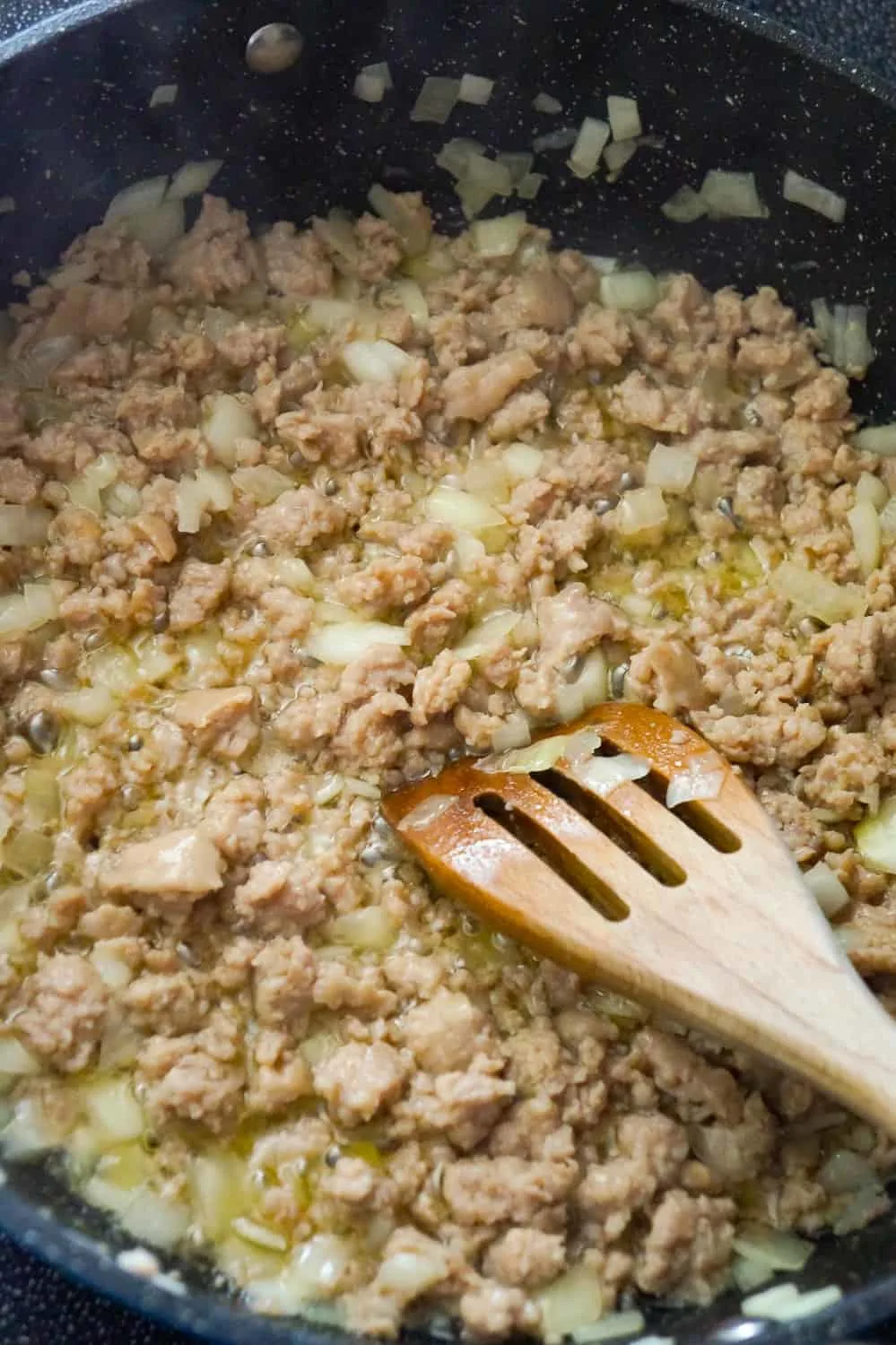 sausage meat and diced onions cooking in a frying pan