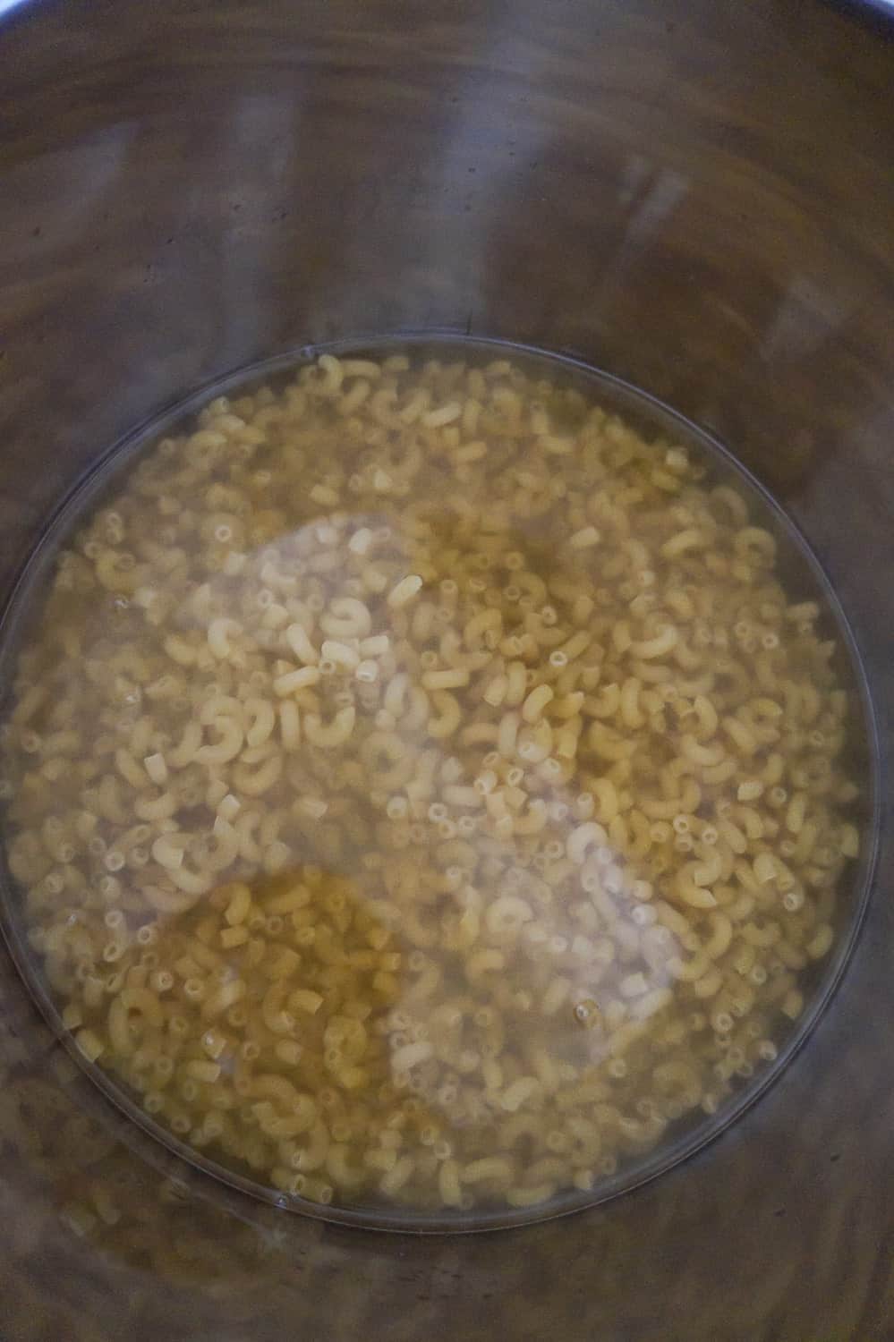 uncooked macaroni submerged in liquid in an Instant Pot