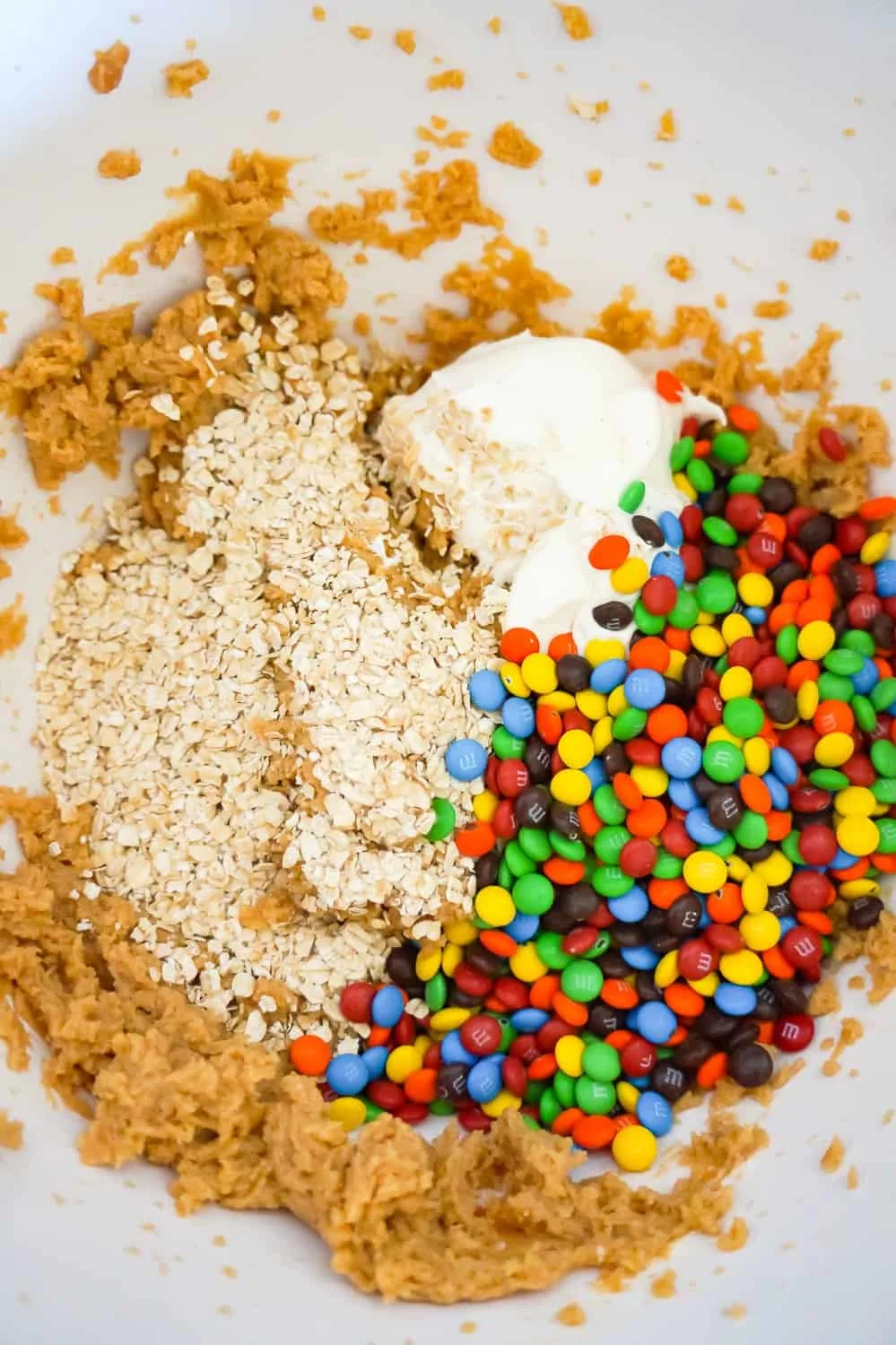 quick oats, Cool Whip and mini M&Ms on top of peanut butter mixture in a mixing bowl