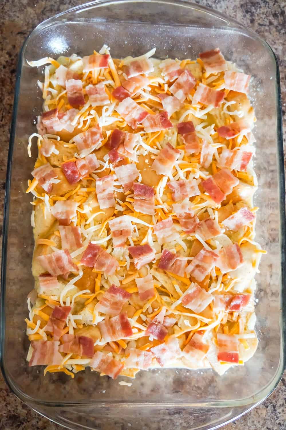 chopped bacon and shredded cheese on top of breakfast casserole before baking