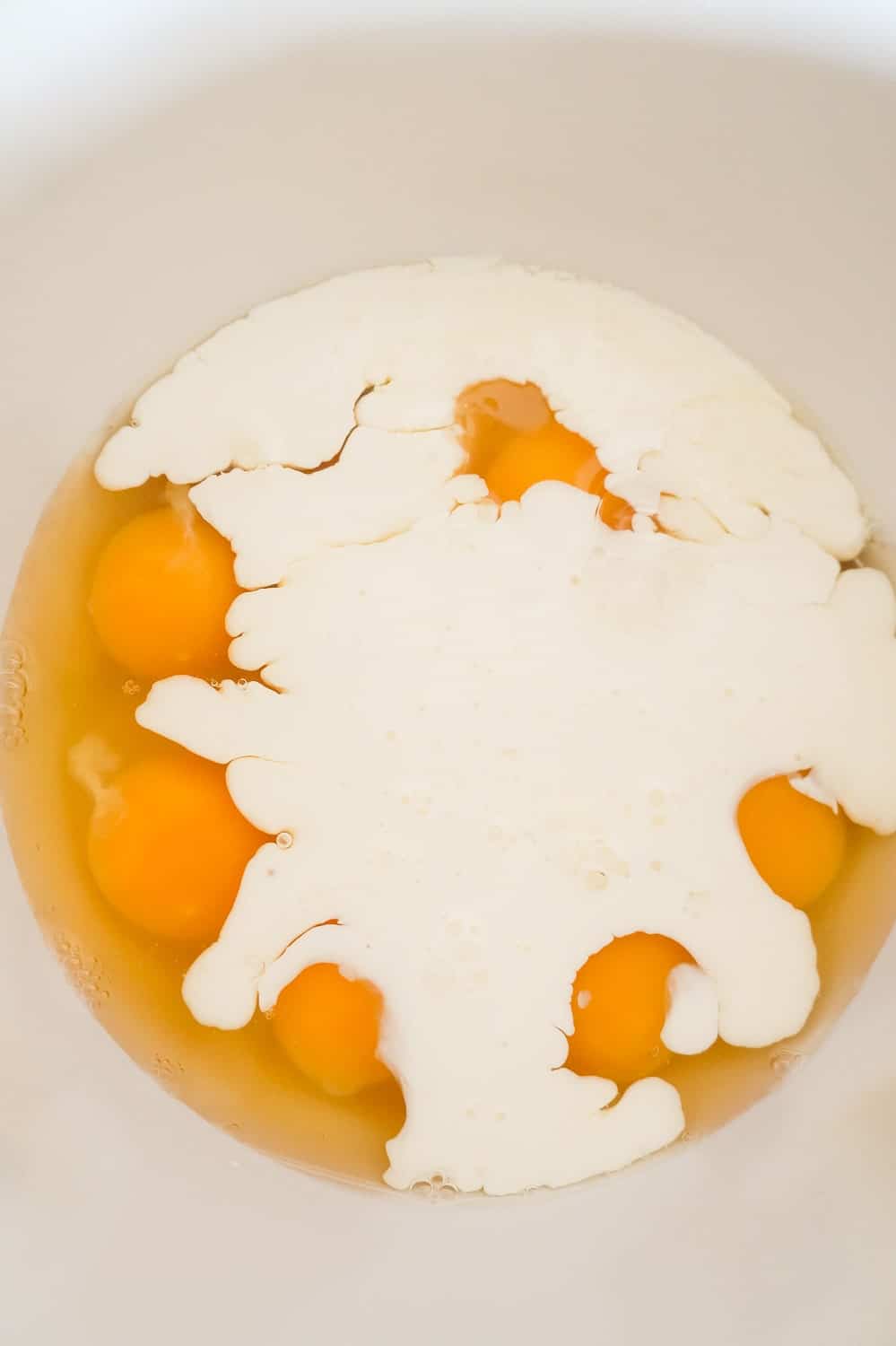 cream on top of eggs in a mixing bowl